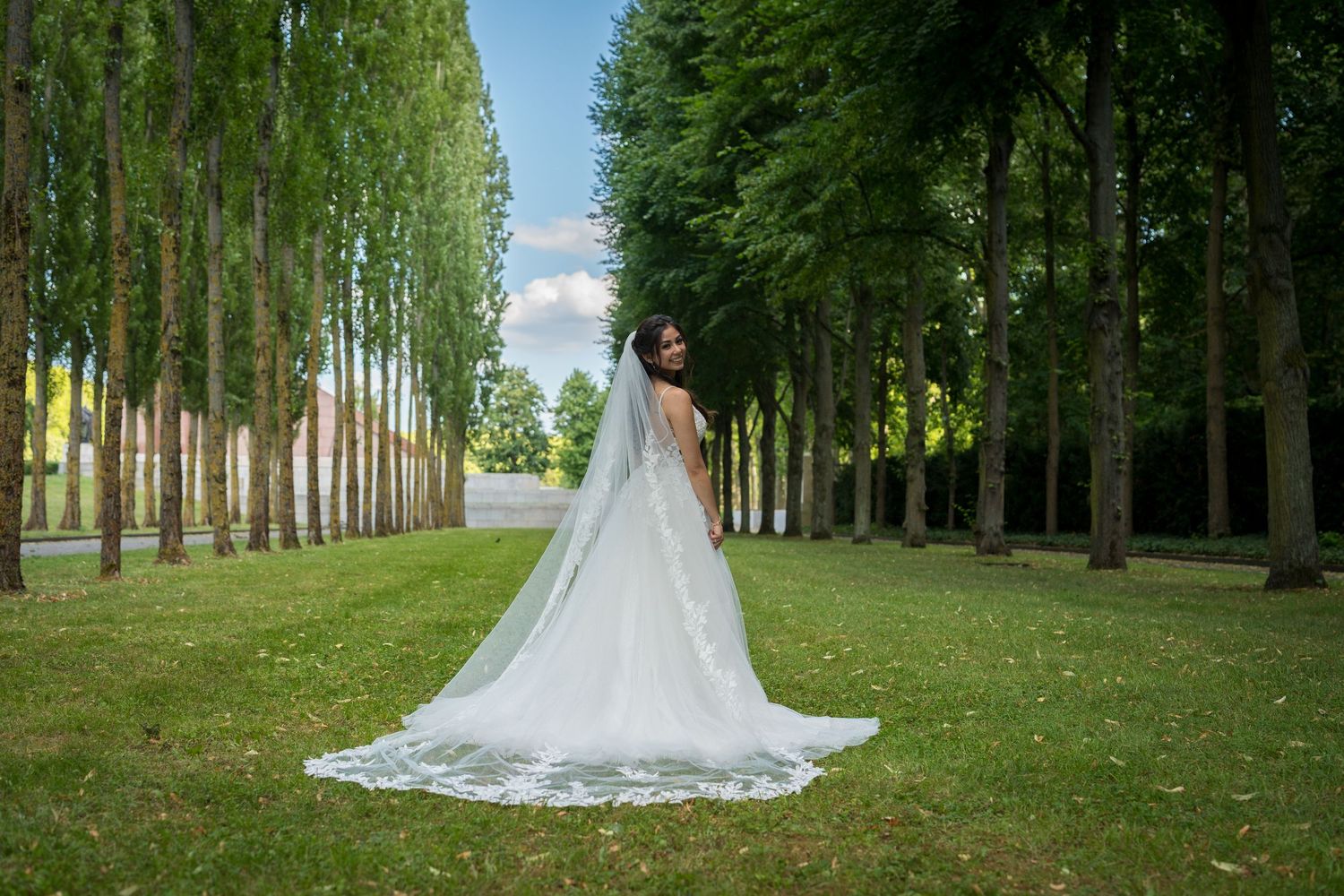 Hochzeitsfotos im Treptower Park Berlin, Braut steht mittig auf einer grünen Allee