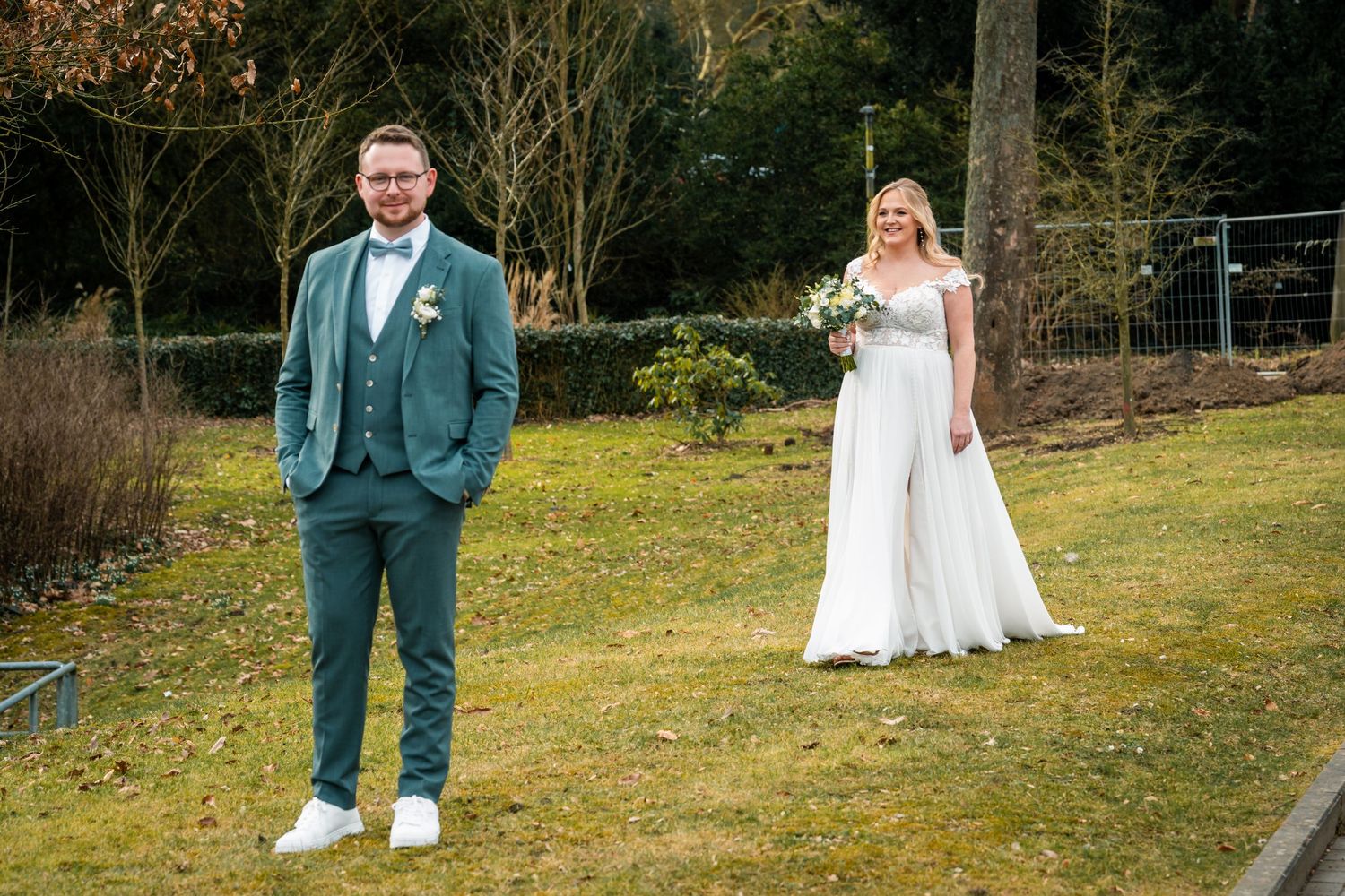 Paarfotos im Park in Dortmund, Braut und Bräutigam stehen mit Abstand im Grünen für ein lockeres Portrait