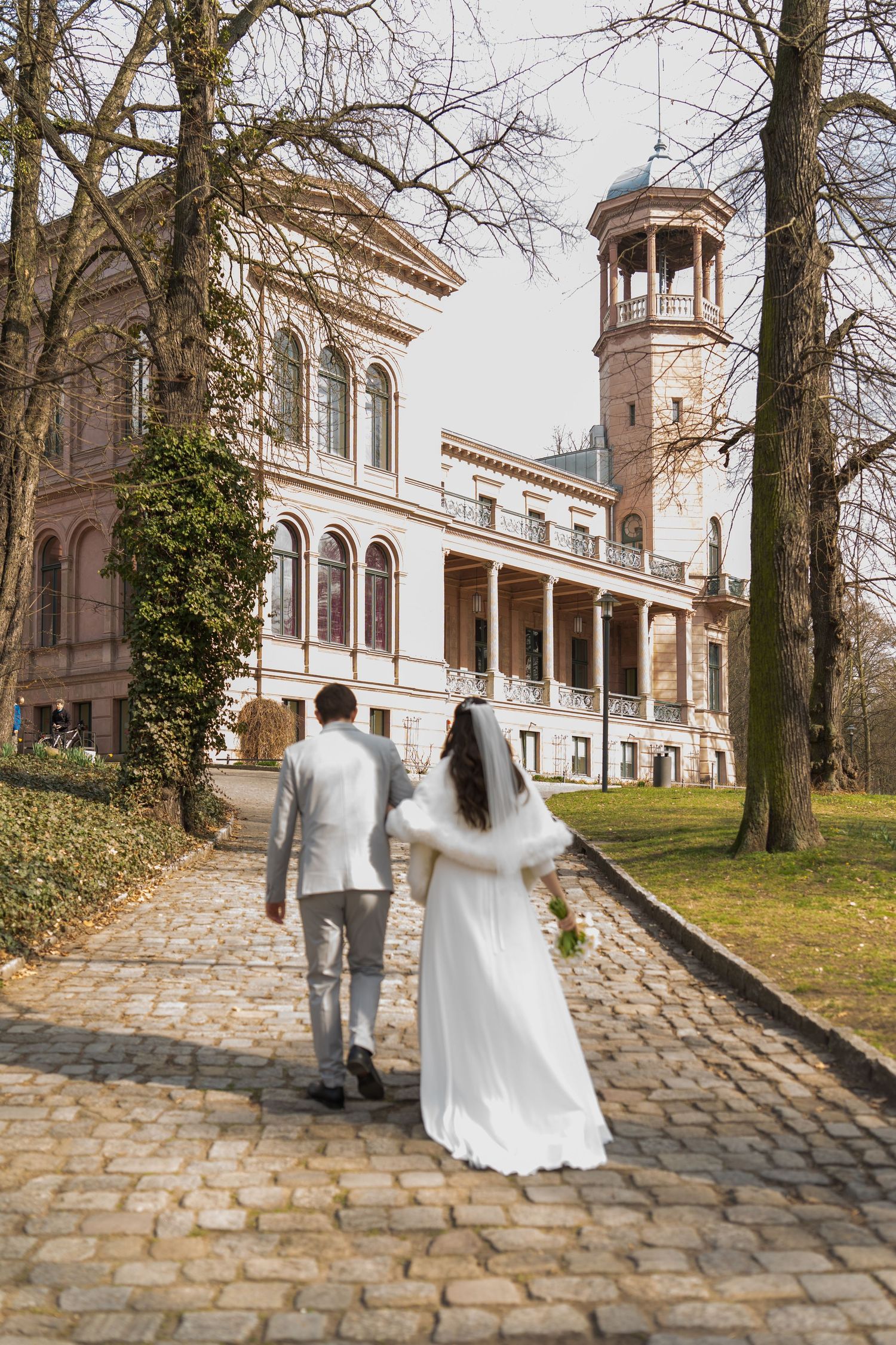 Brautpaar geht gemeinsam über den Schlossvorplatz nach der Trauung