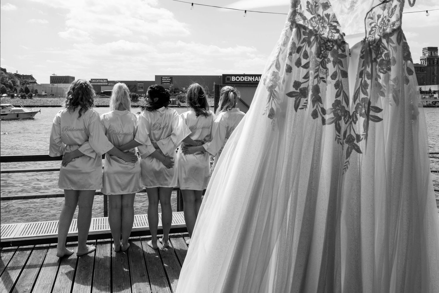Freie Trauung an der White Spreelounge Berlin, Detailaufnahme des Brautkleides mit Blick auf die Freundinnen am Wasser