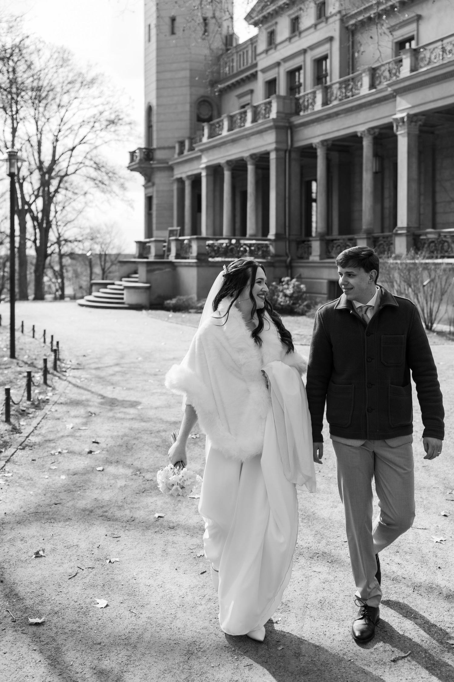 Brautpaar spaziert gemeinsam vor dem Schloss Biesdorf in Berlin nach der Hochzeit