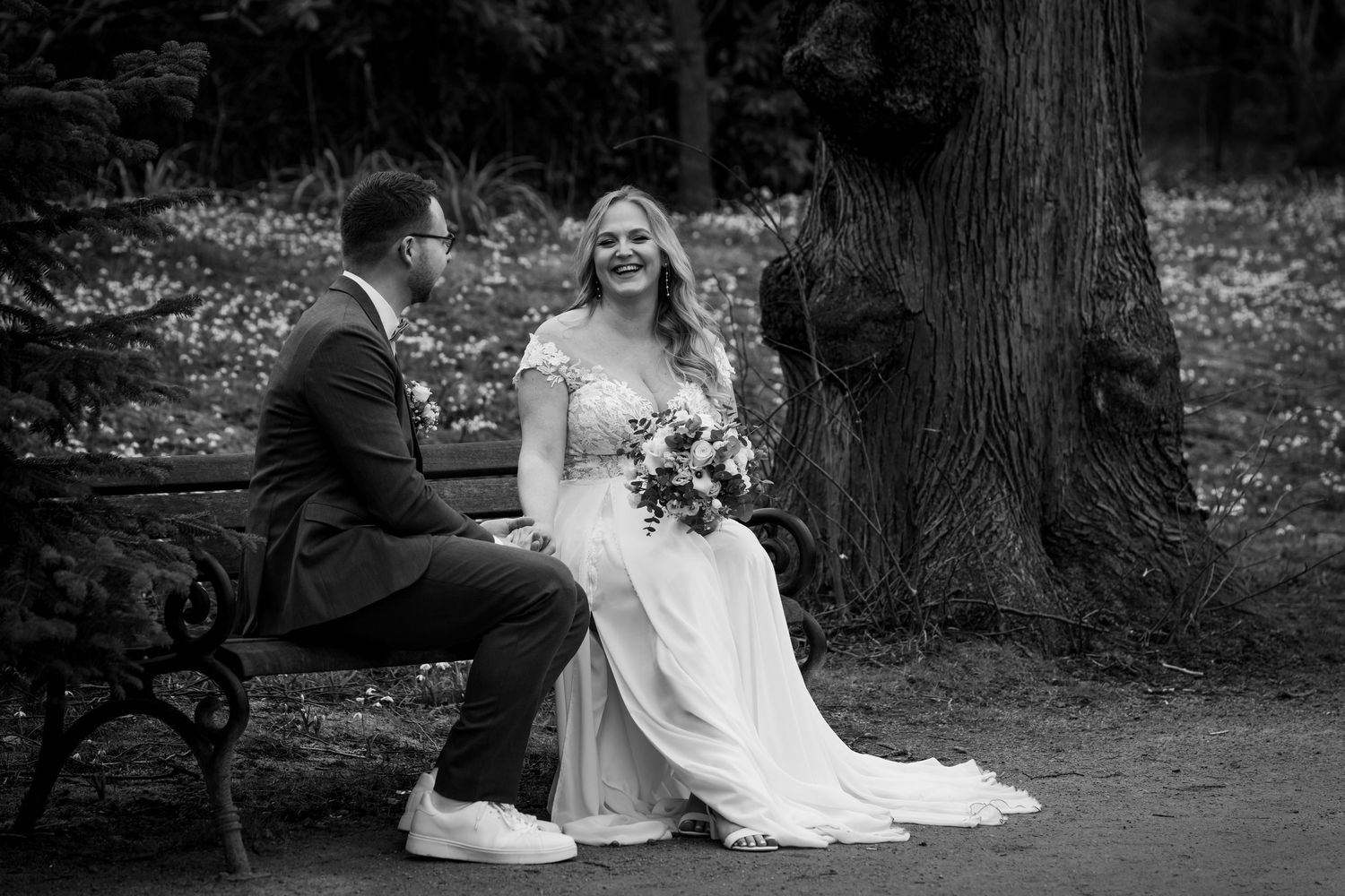 Paarfotos im Park in Dortmund, entspanntes Brautpaar sitzt gemeinsam auf einer Parkbank
