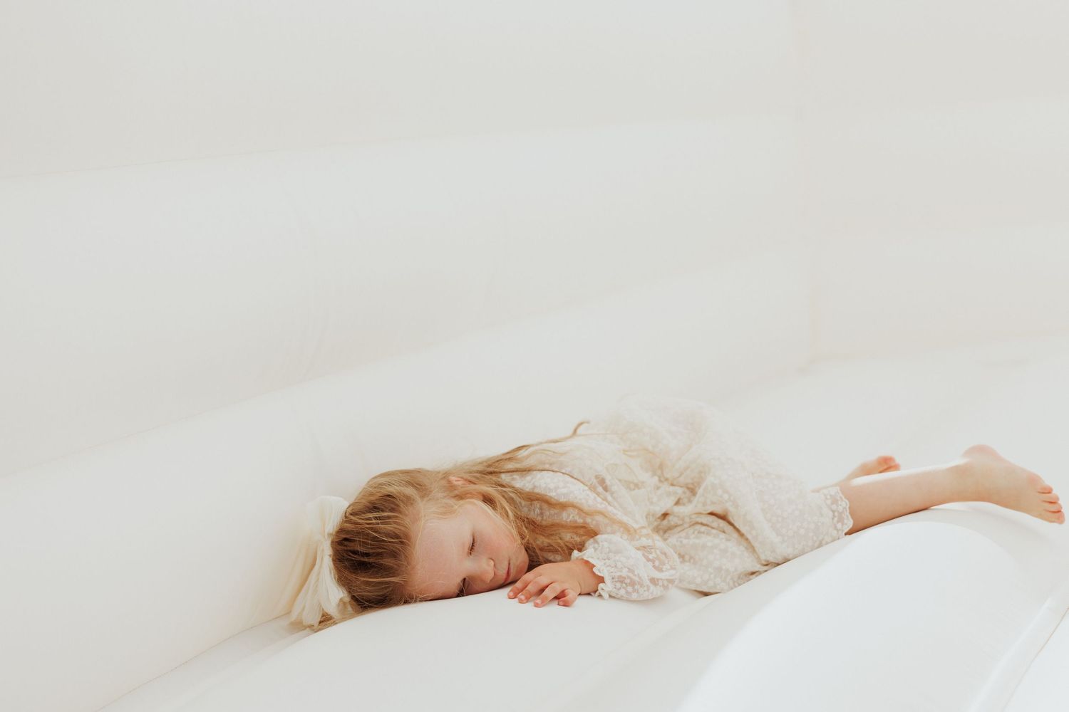 Soft and dreamy minimalist photograph on white bedding with gentle natural light.