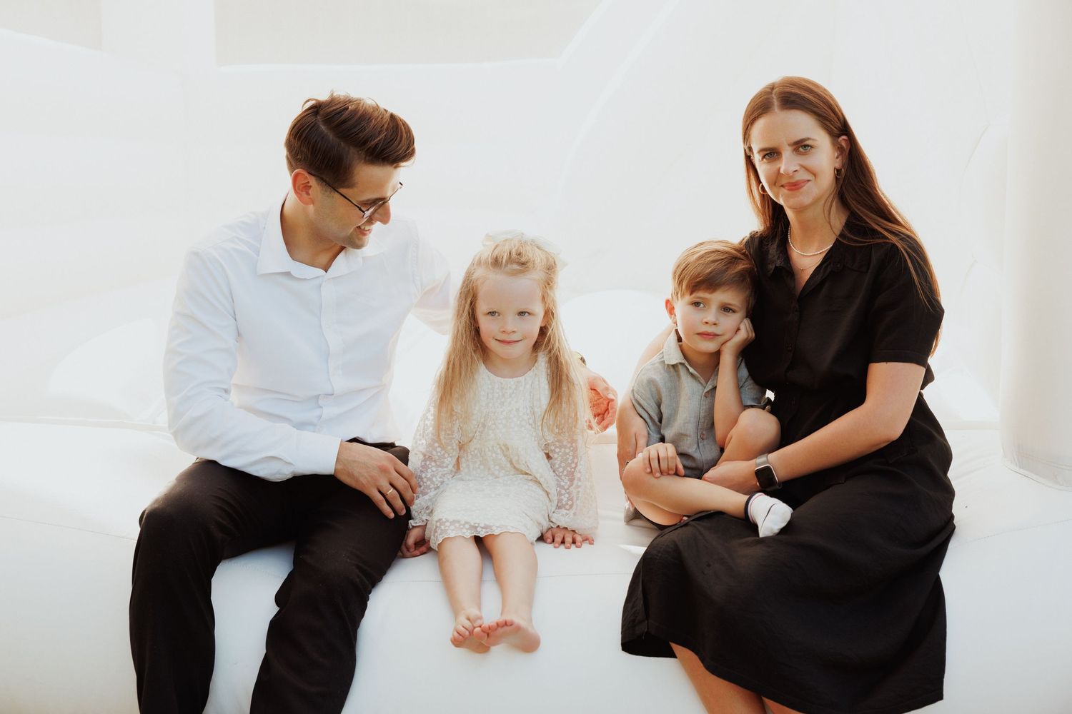 Indoor family photo session with minimalist white backdrop and casual styling.