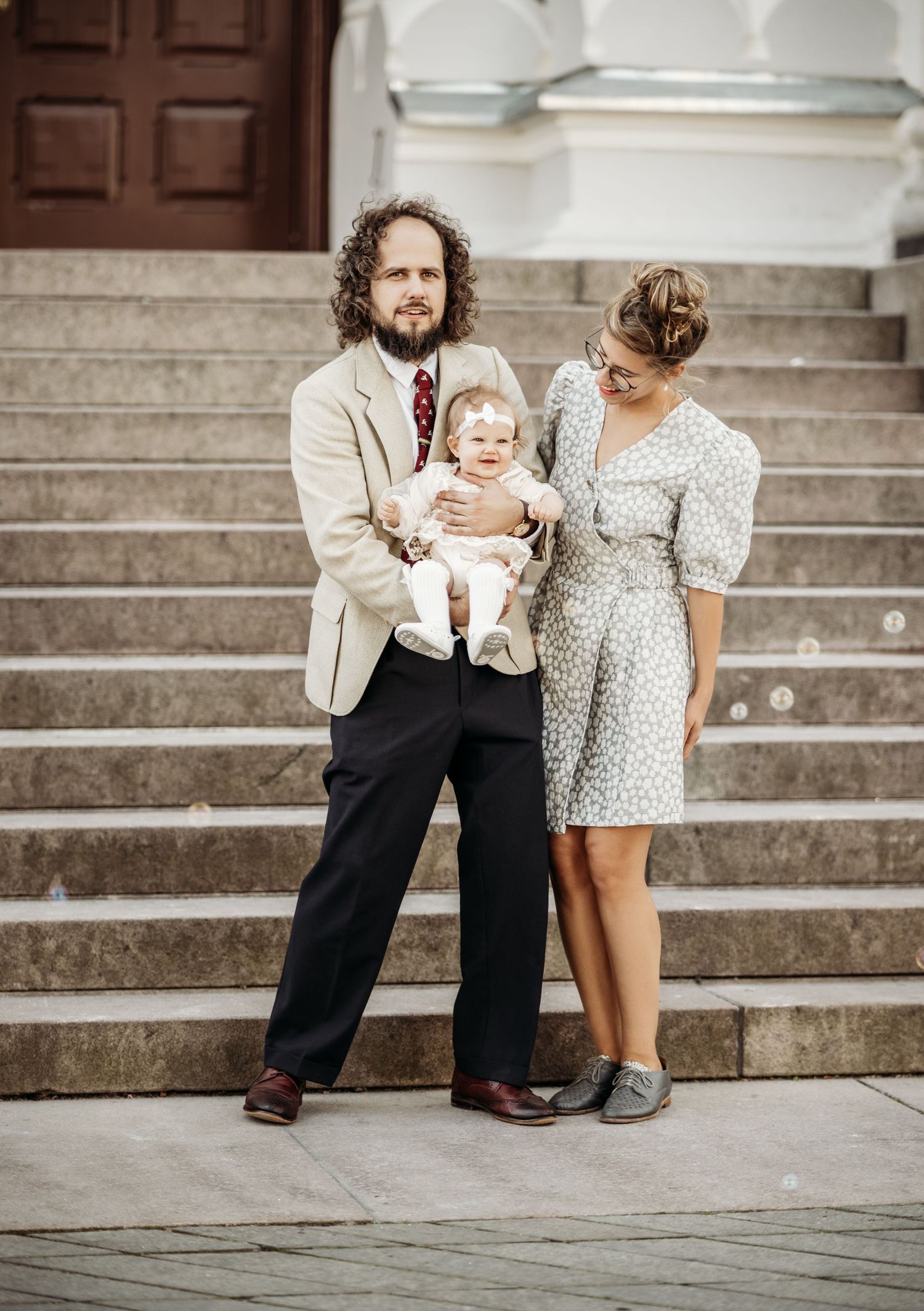 A sweet family moment captured on stone steps with a small child in a polka dot dress.