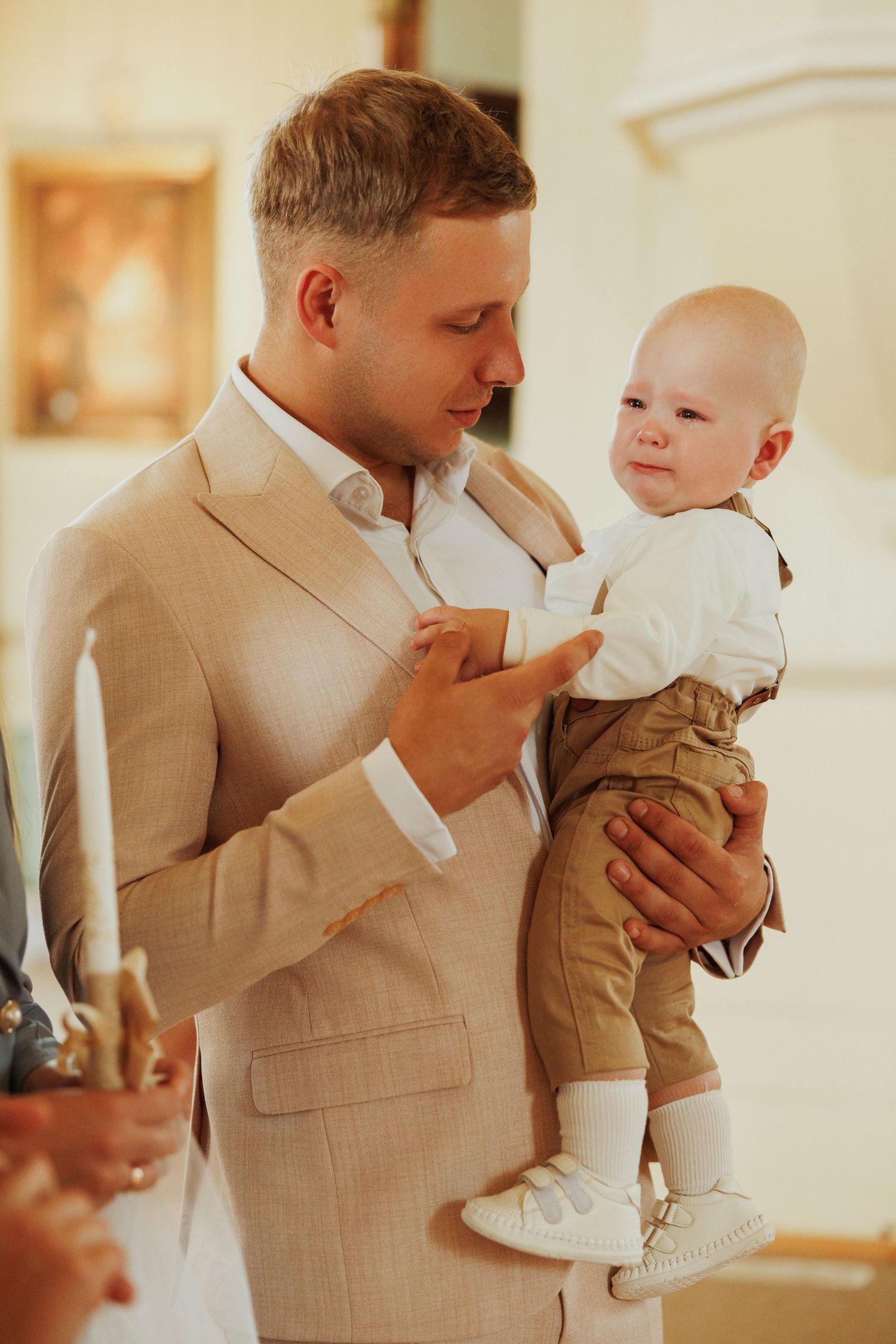 A tender moment captured between a parent and child in formal beige attire at an indoor event.