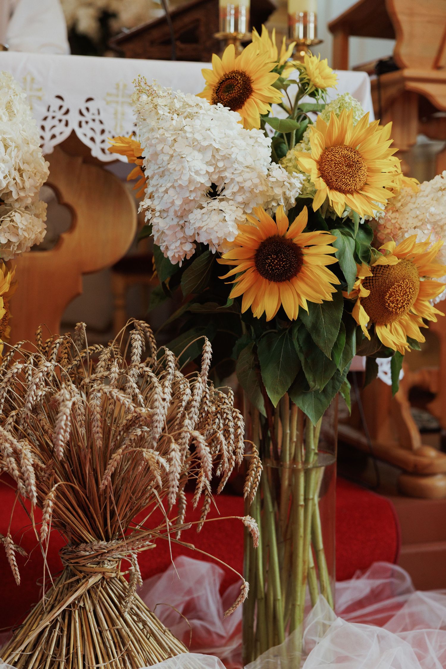 Rustic floral arrangement with bright sunflowers, white hydrangeas and wheat bundles.