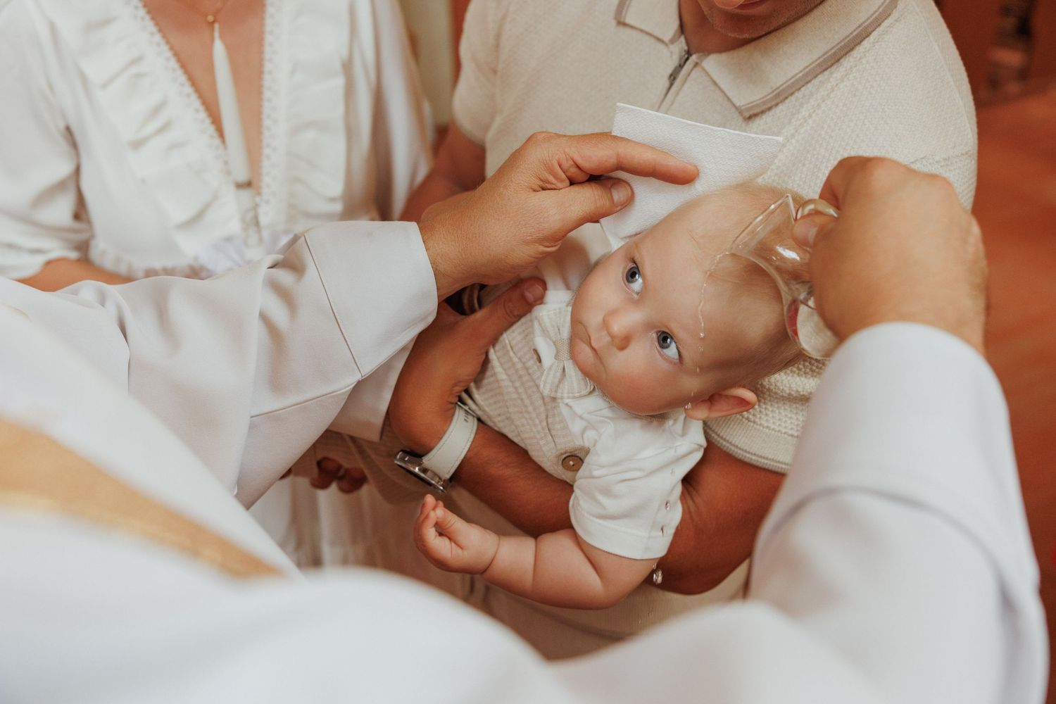 A series of intimate close-up shots showing tender moments between parent and infant in white clothing.