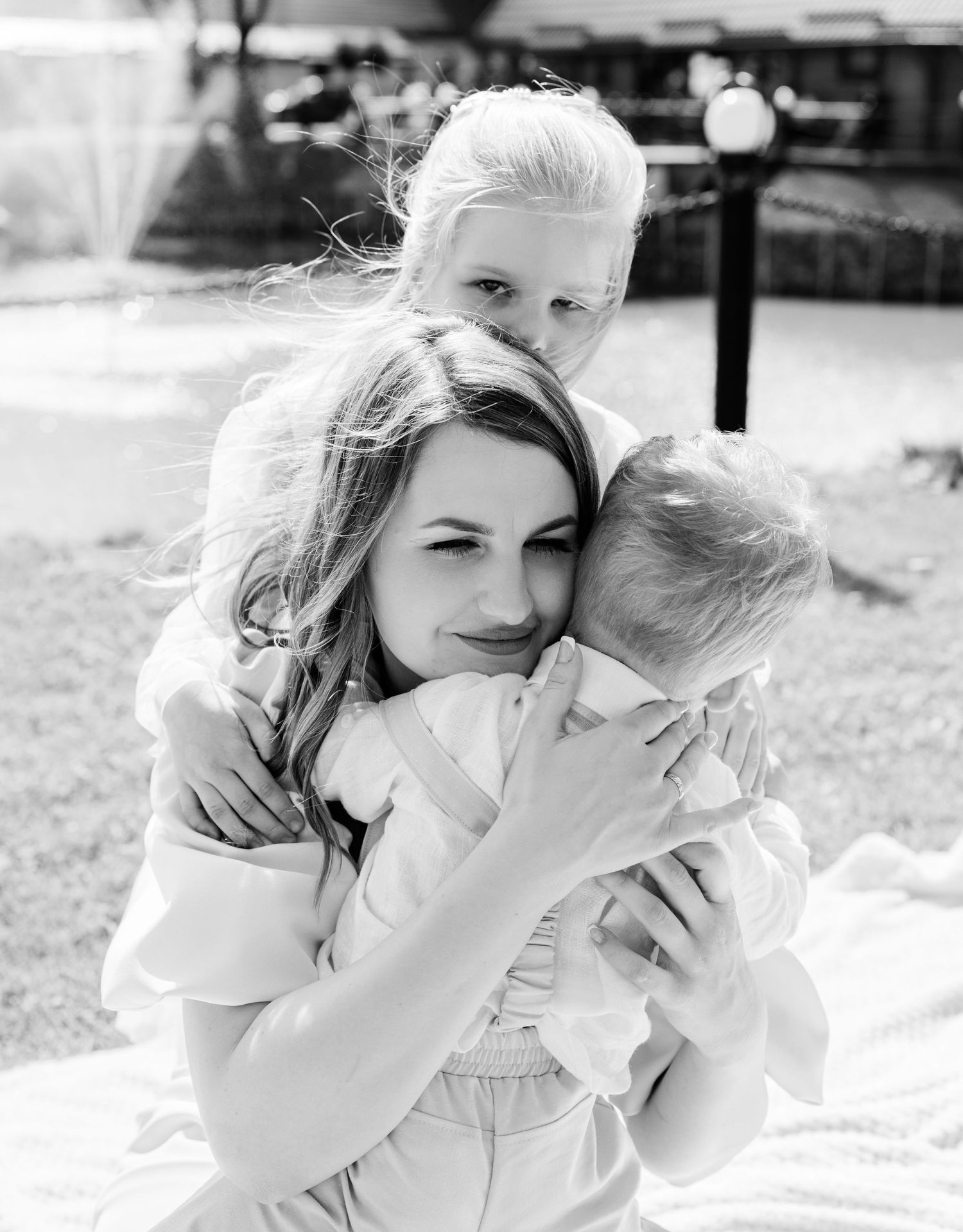 Black and white photo series showing tender moments between parent and child outdoors on a sunny day.