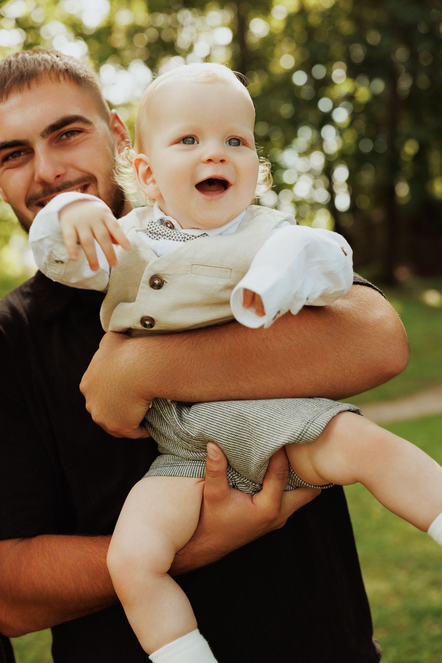 Playful moments of baby being held up in the air against sunny outdoor background.