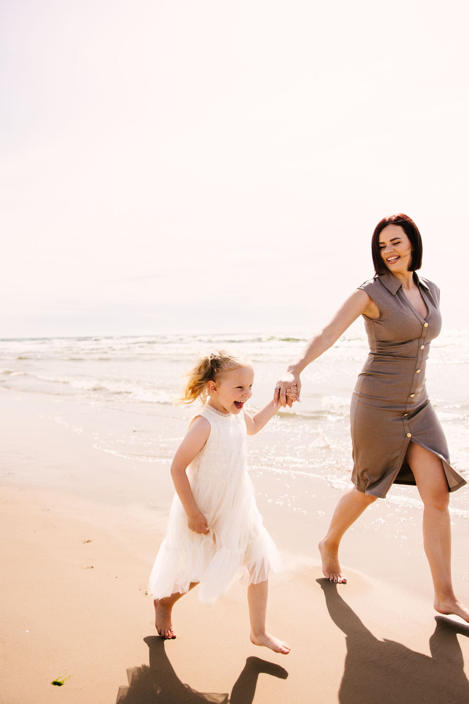 Playful sequence of two people dancing and jumping together on a sunlit beach at sunset.