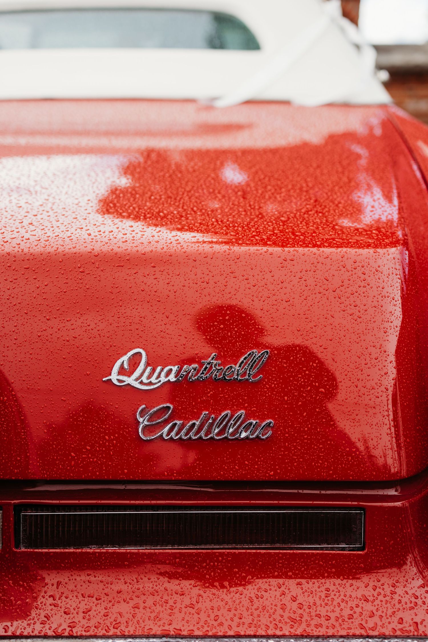 Close-up detail shots of red Cadillac emblems and badges on a classic car exterior.