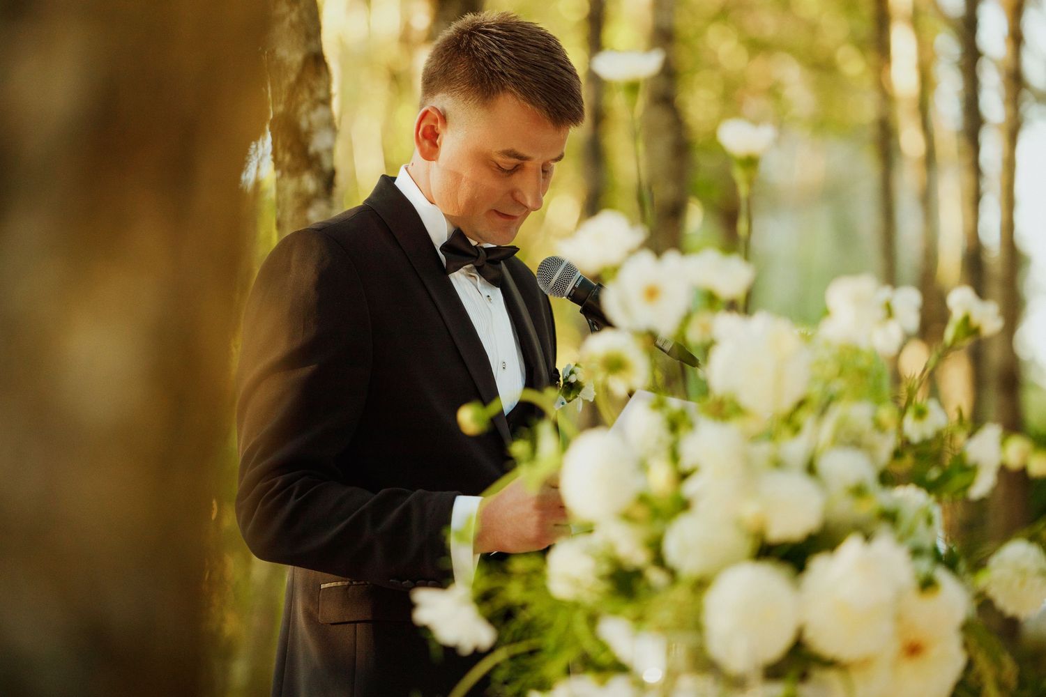 Elegant wedding details with white flowers and greenery in natural forest lighting.
