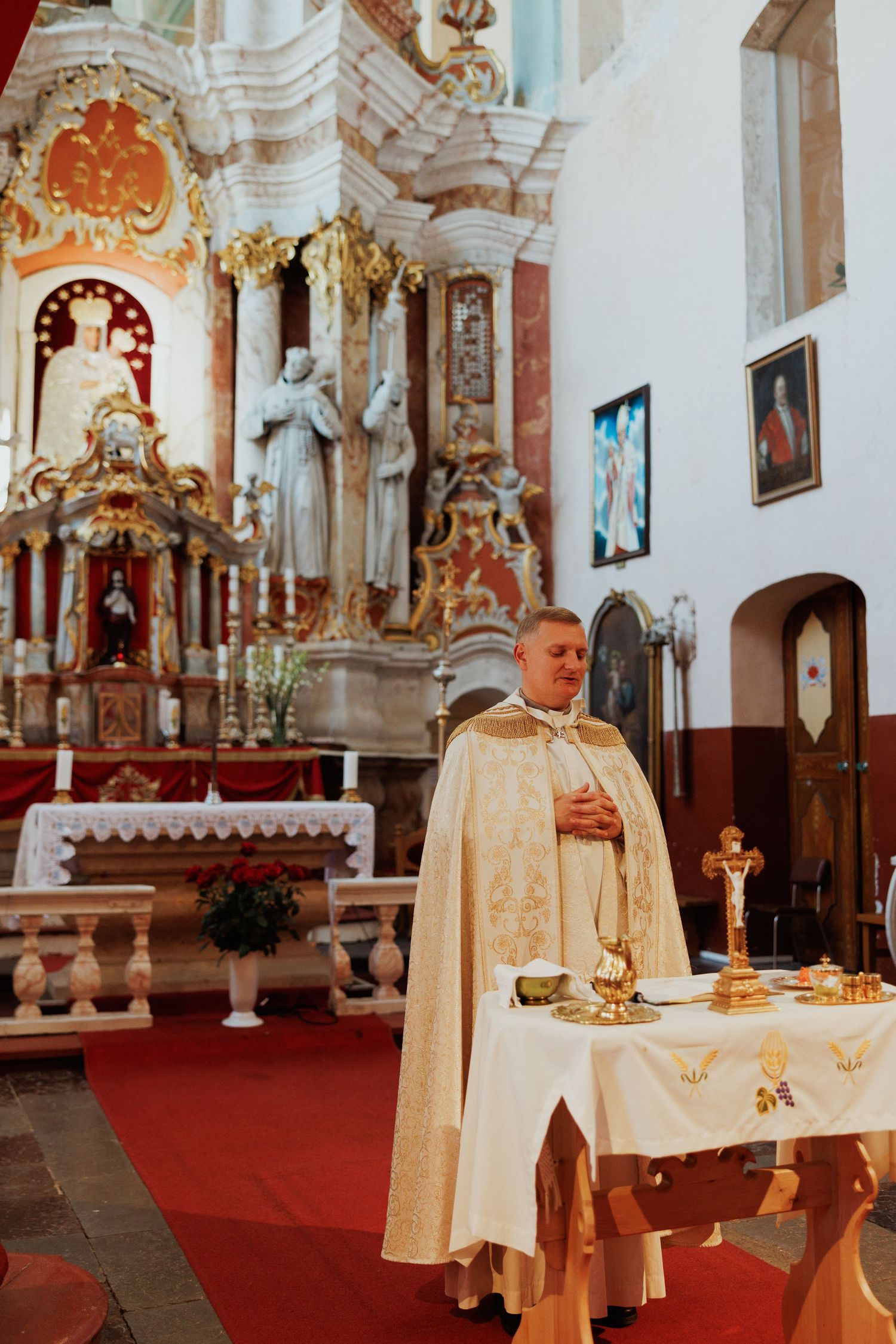 An ornate church interior with gold decorations and white altar cloths on display.