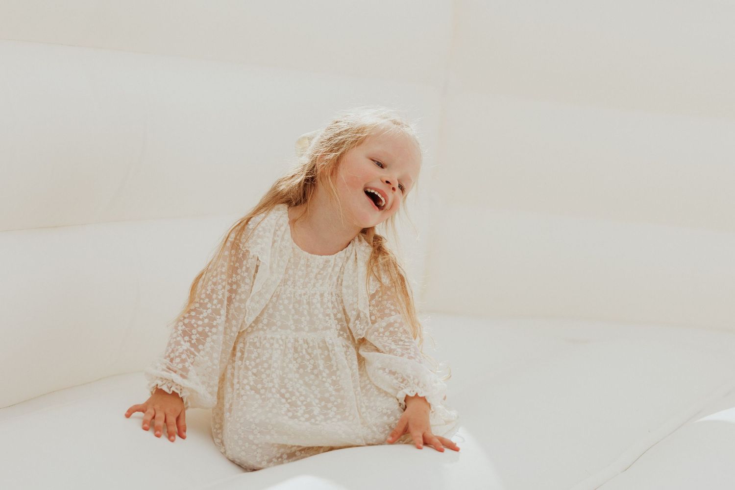 White lace dress details against a bright neutral background.