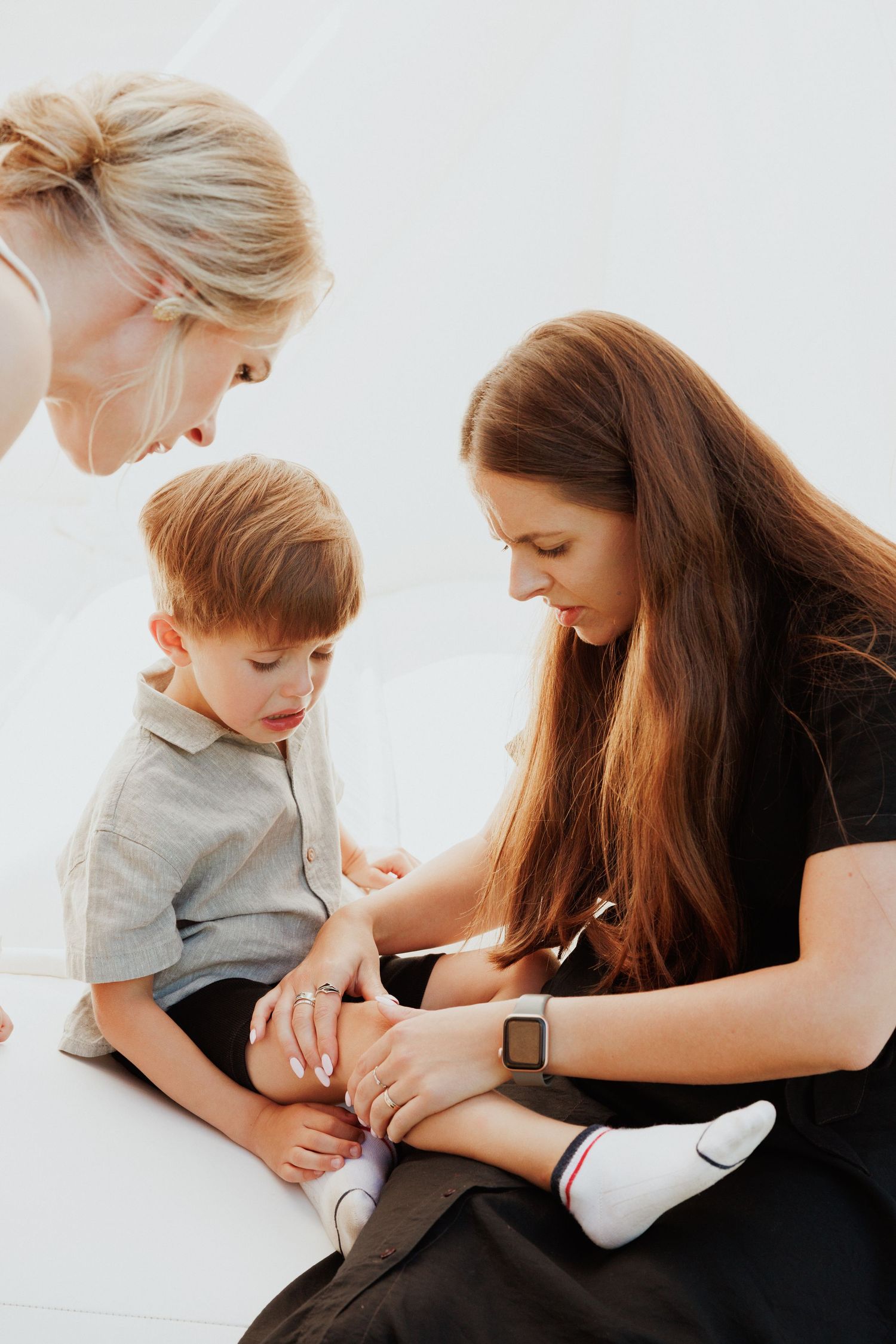 Intimate family moment captured during casual indoor photo session with white backdrop.