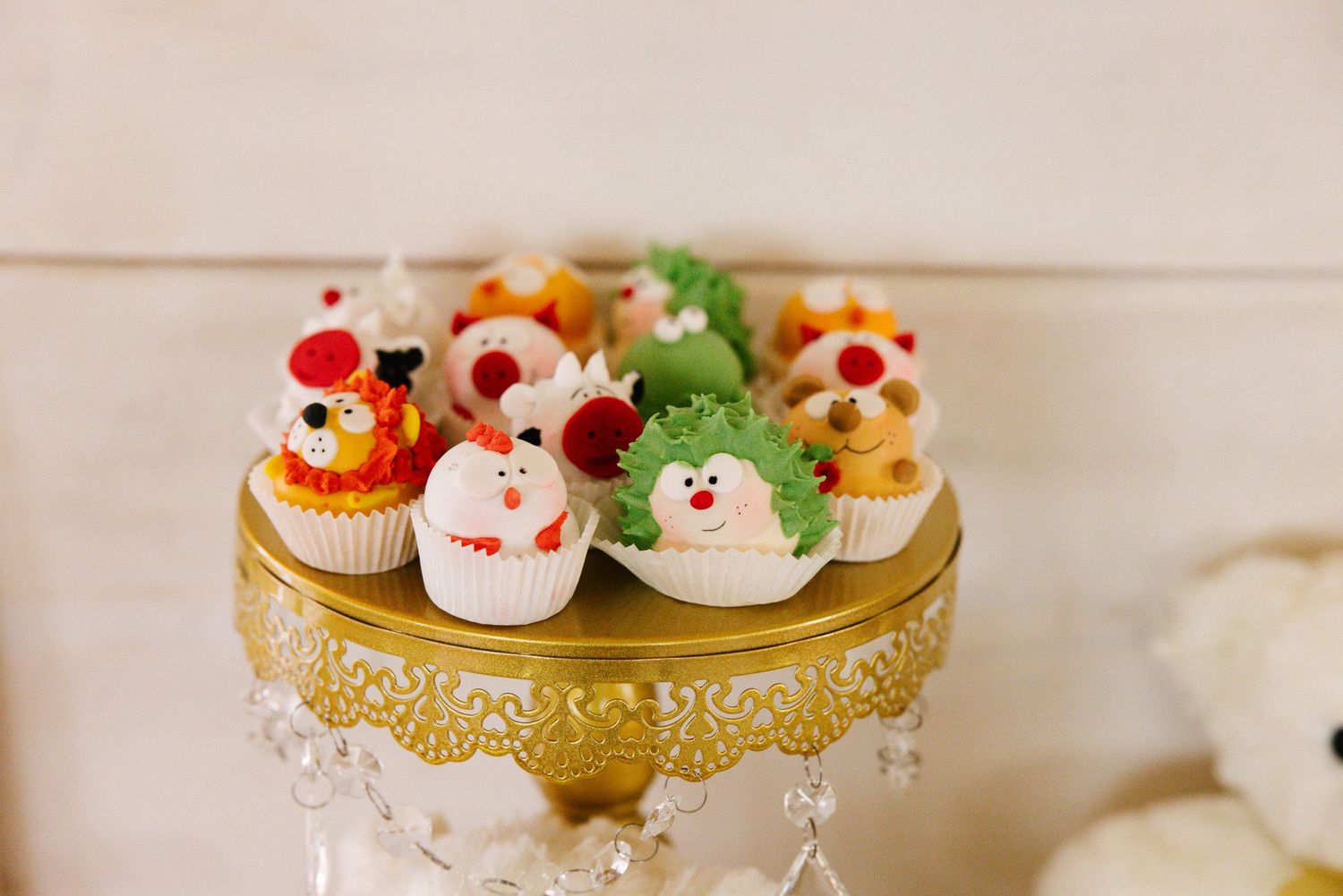 Colorful cupcakes with festive decorations displayed on an ornate gold cake stand.