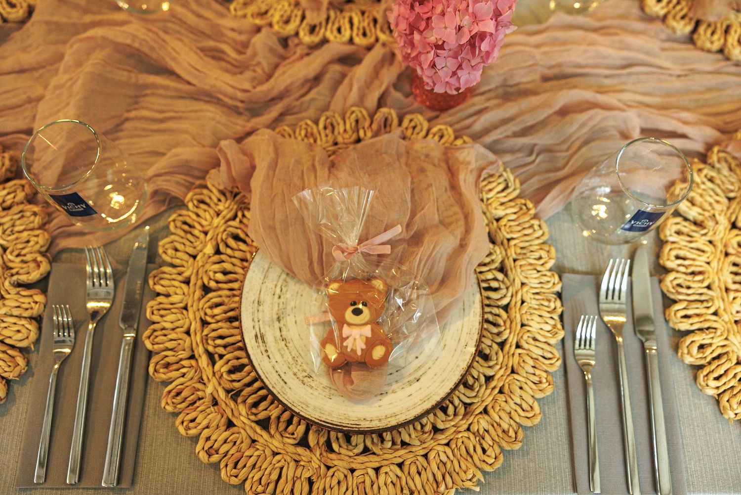Elegant place setting featuring gold charger plates and cutlery on a wooden table surface.