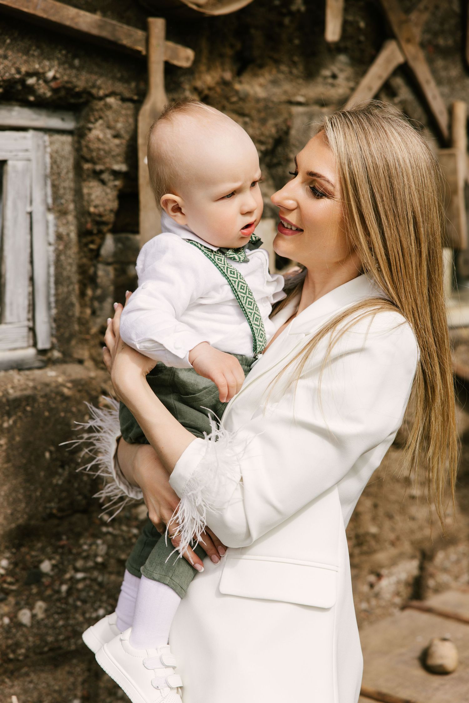 A sweet moment shared between parent and baby dressed in white and grey formal attire.