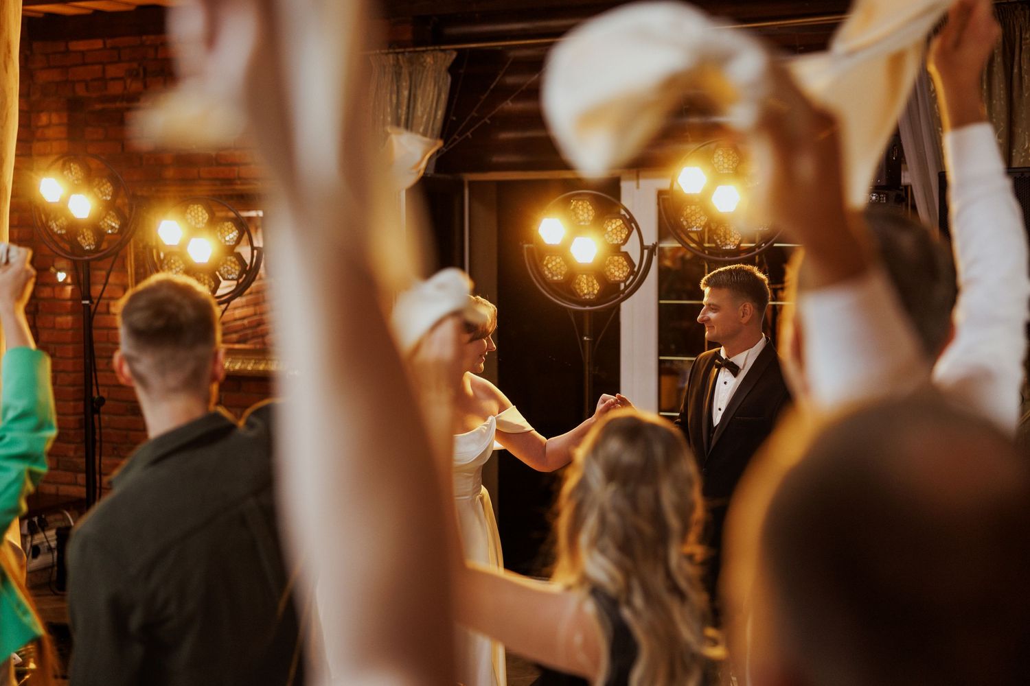 Wedding guests dance and celebrate on an illuminated dance floor during an evening reception.