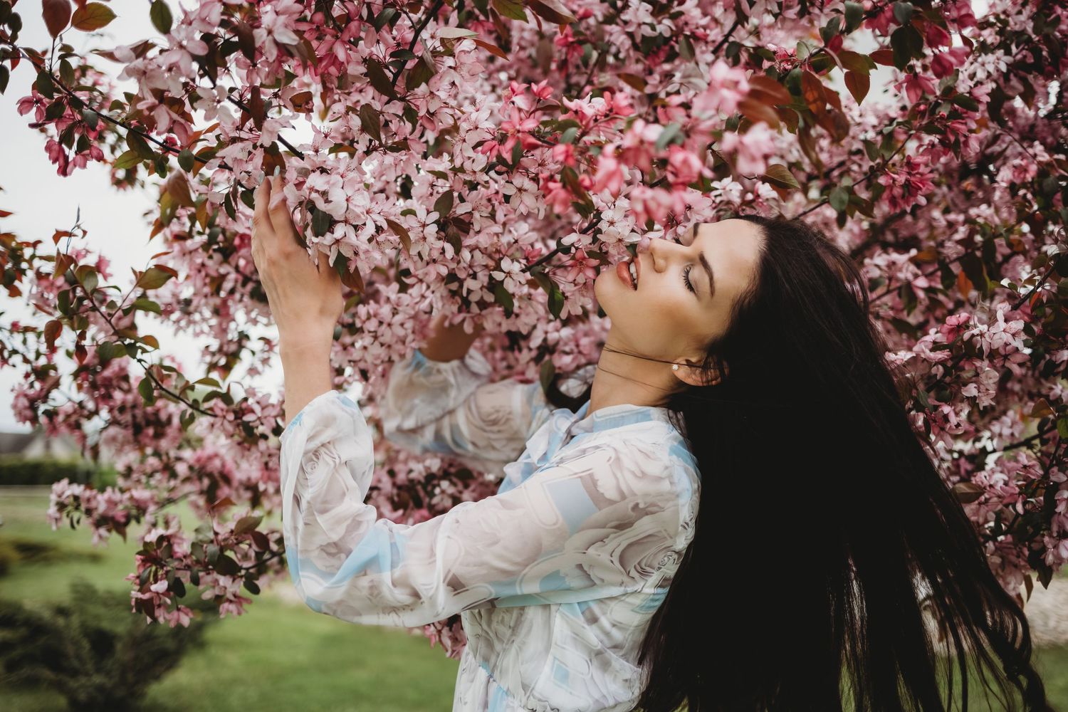 Dreamy spring photoshoot beneath pink cherry blossom branches in full bloom.
