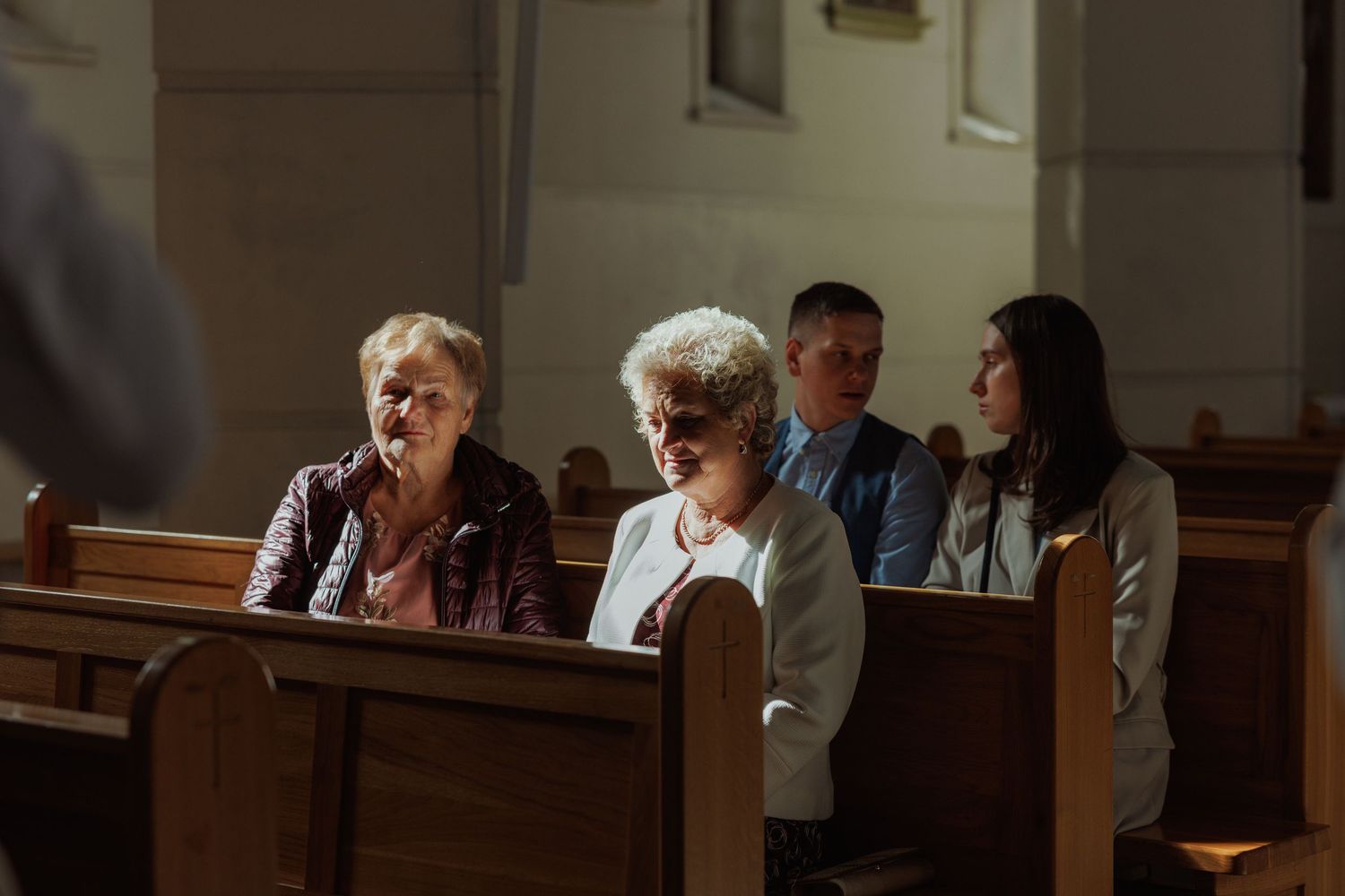 A group of people gather in a church pew during a religious service.