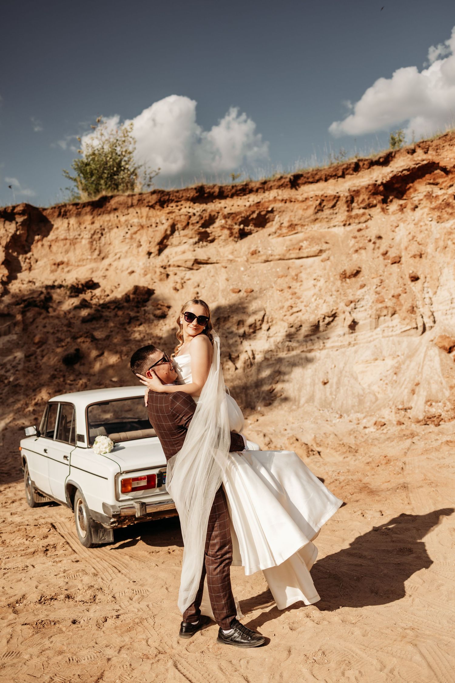 Vintage white pickup truck parked against a rustic desert cliff backdrop.