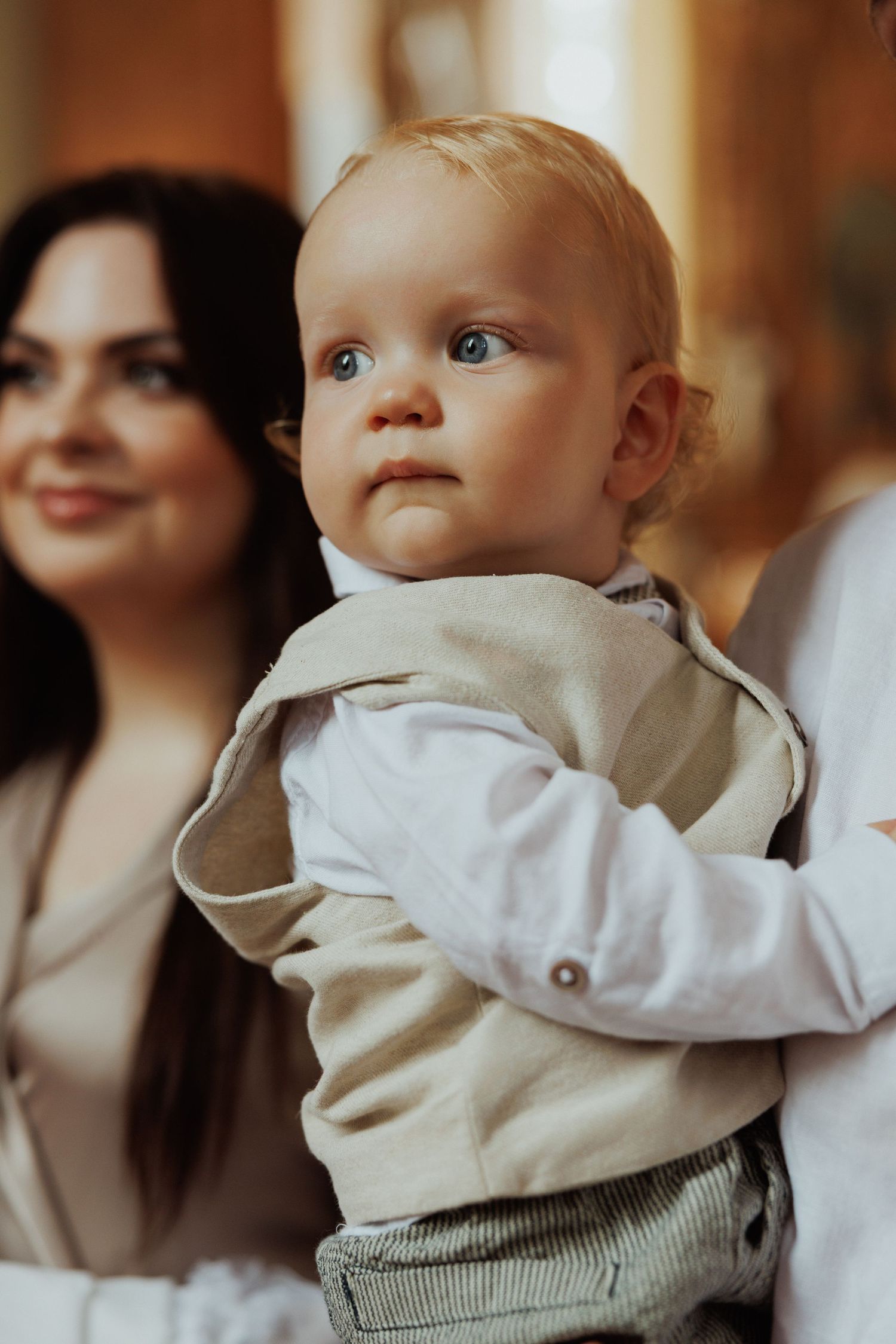 Close-up portraits of a baby in white clothing looking up with curious expressions.
