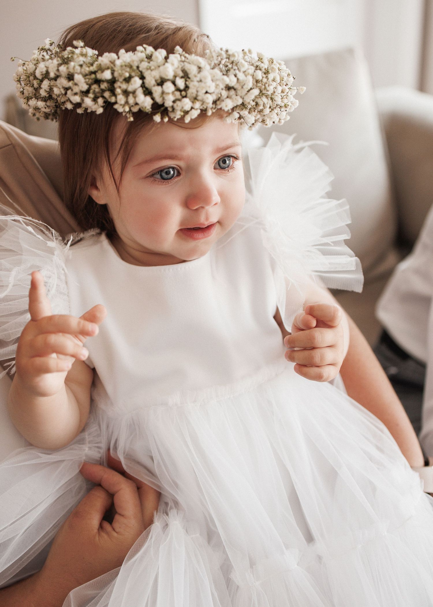 A baby in a white tulle dress and floral crown poses in multiple candid shots against a light background.