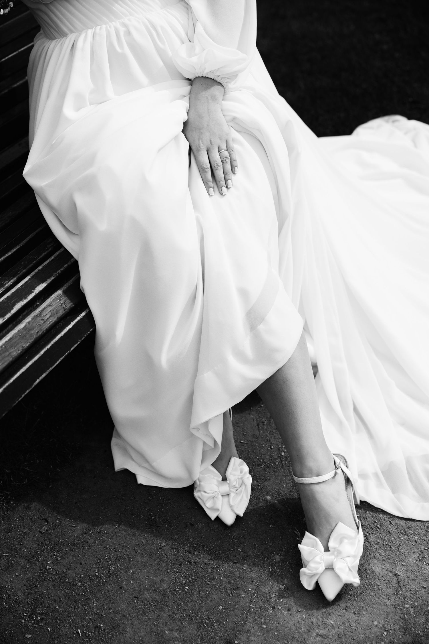 Close-up detail of a white wedding dress and decorative bridal shoes with bow accents.