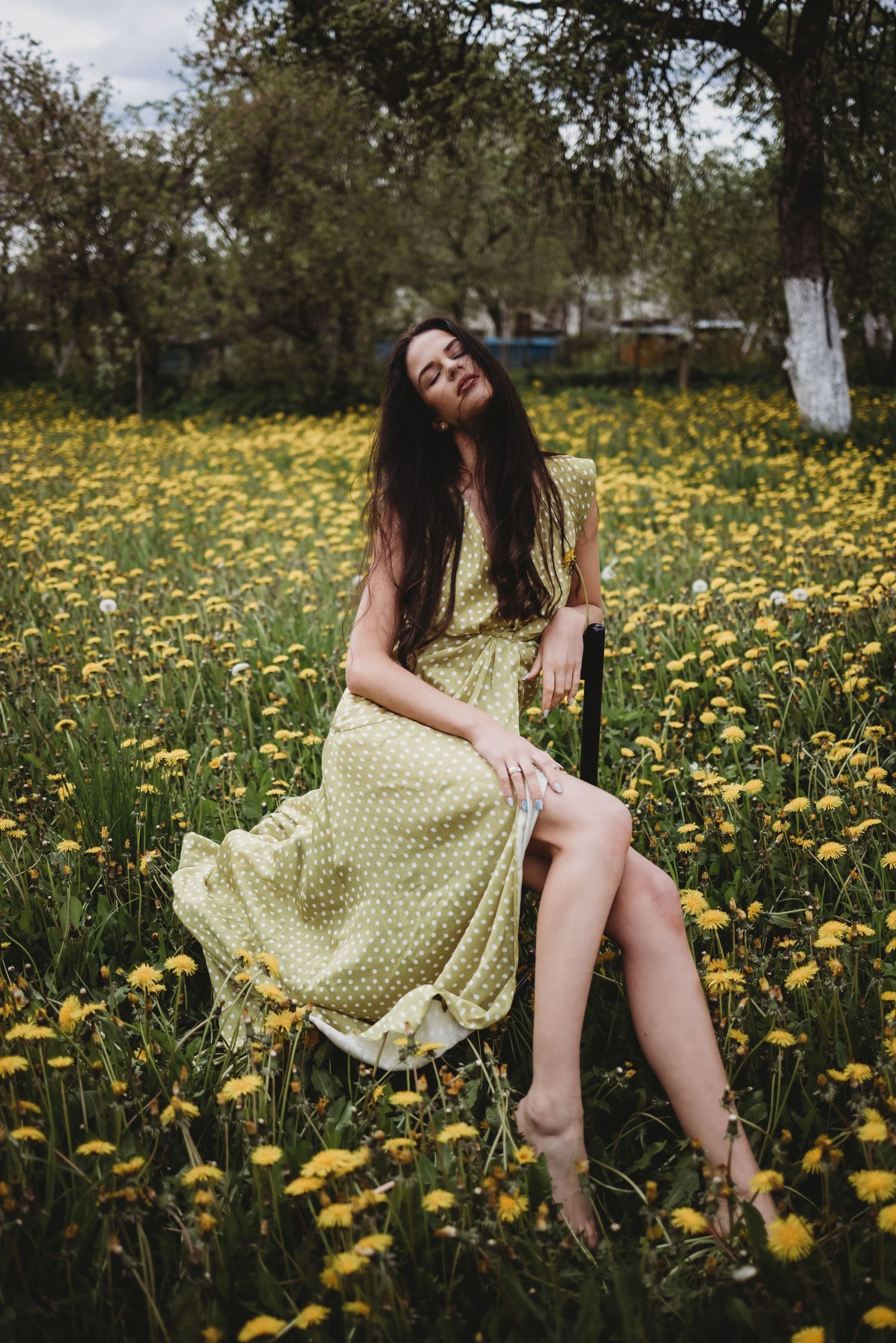 Dreamy scene in a field of yellow dandelions with flowing polka dot dress.