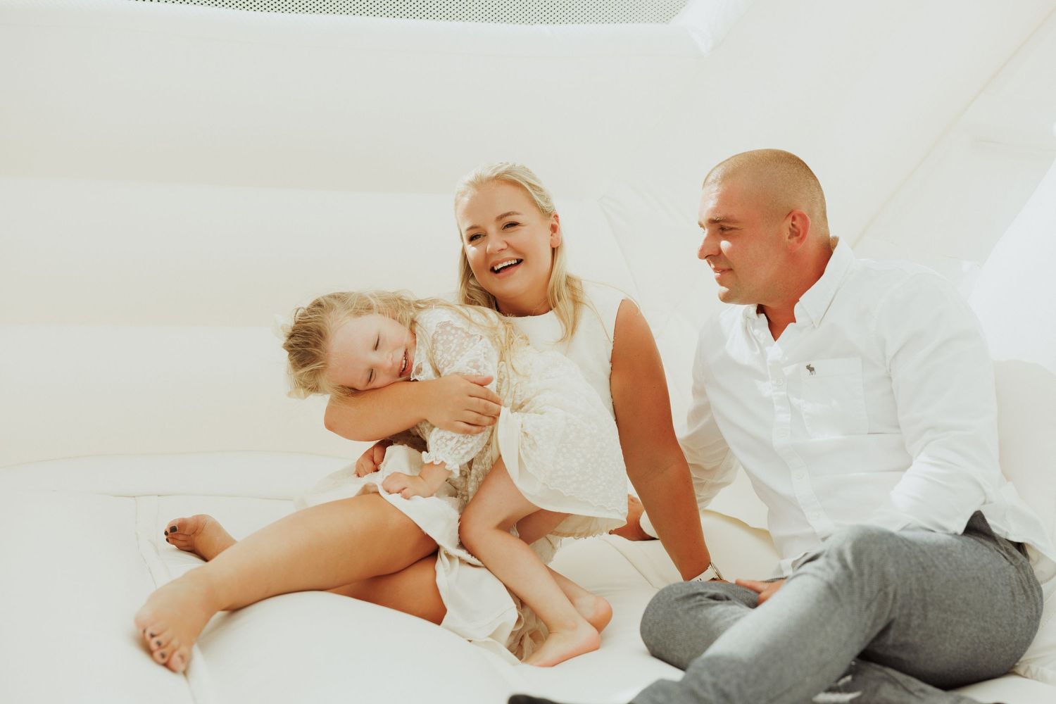 A family shares a joyful moment together inside a white bounce house.