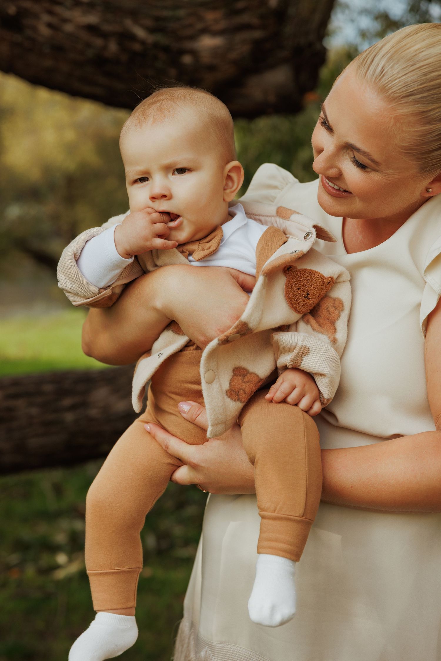 A series of photos showing a baby in beige overalls and white shirt being held and cuddled outdoors.