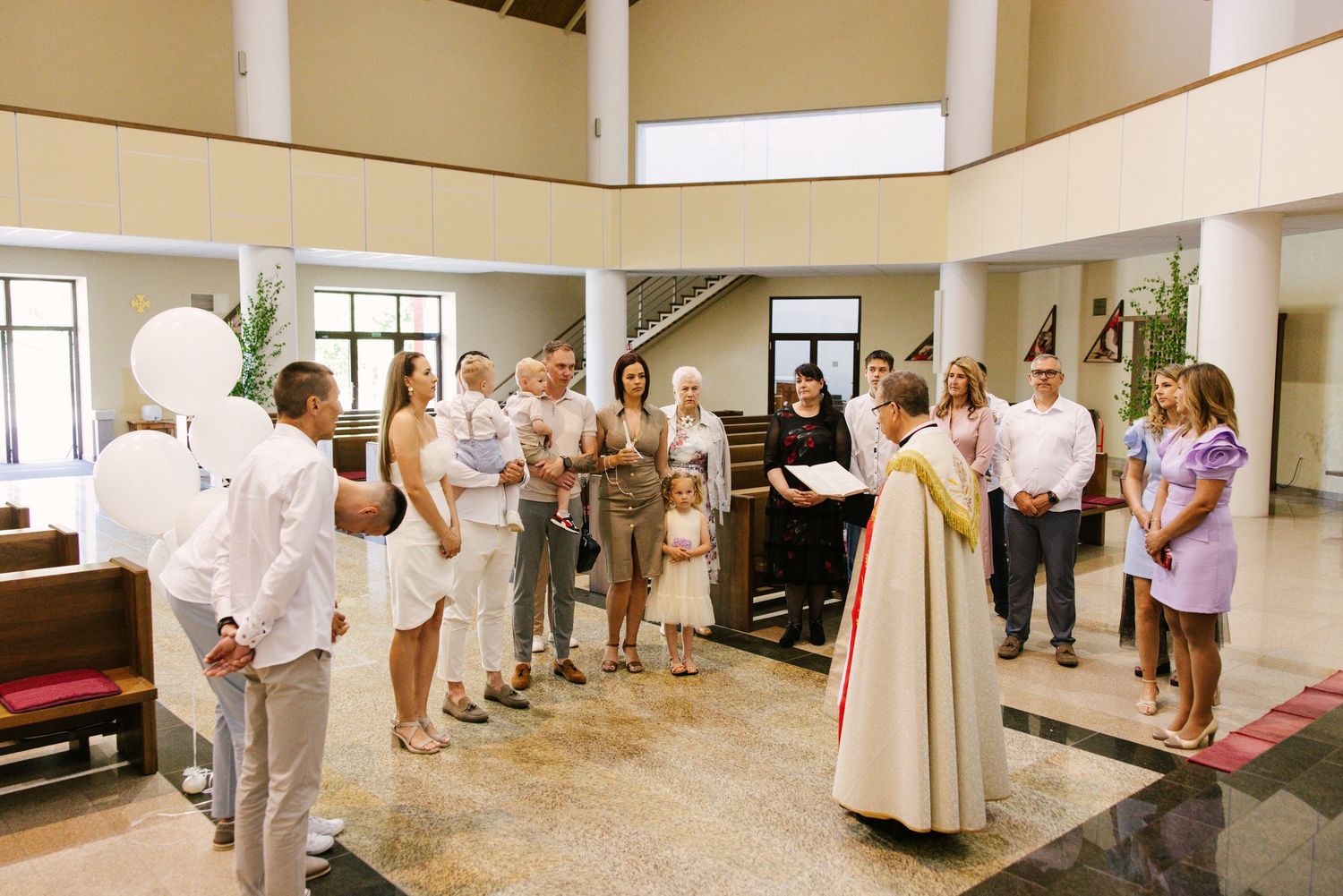 Interior view of a church baptism service with attendees standing in rows.