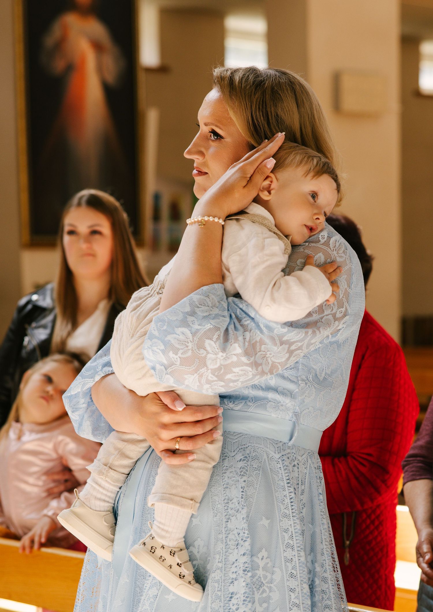 A series of candid moments showing a person in red holding a baby wearing a delicate blue lace dress.