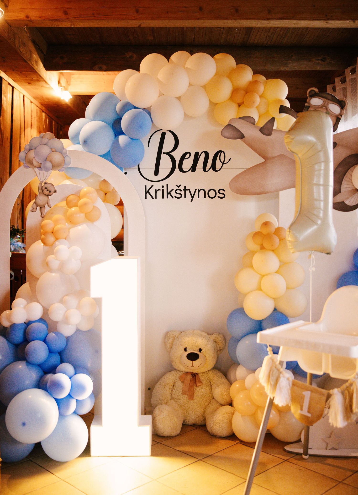Baby shower decoration with blue and cream balloon arch and teddy bear theme.
