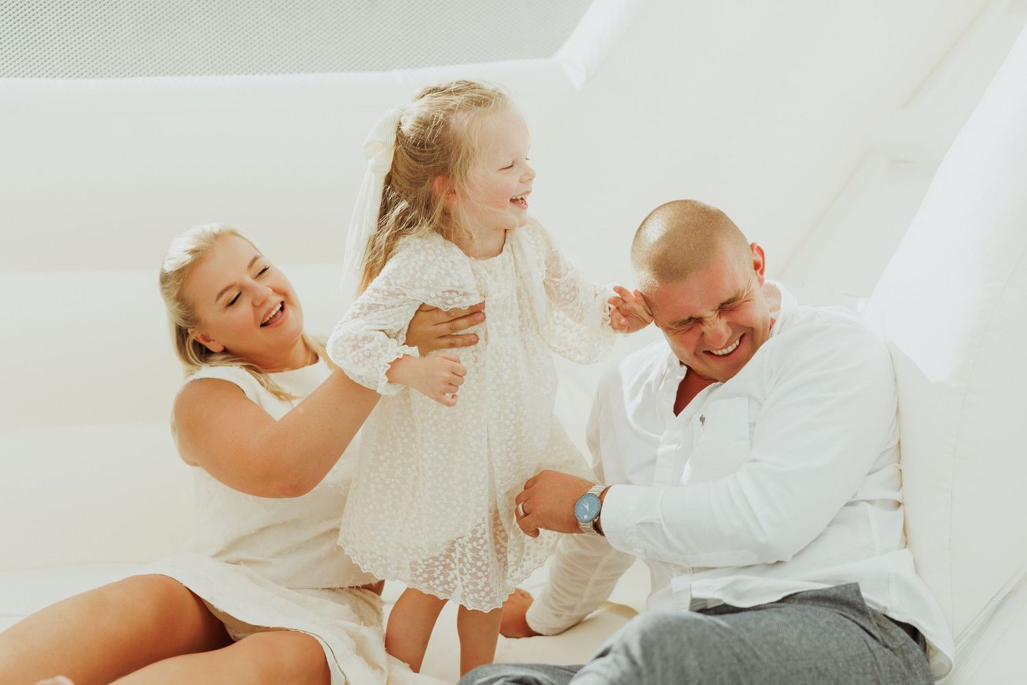 Family enjoying intimate moments together on white backdrop during photo session.
