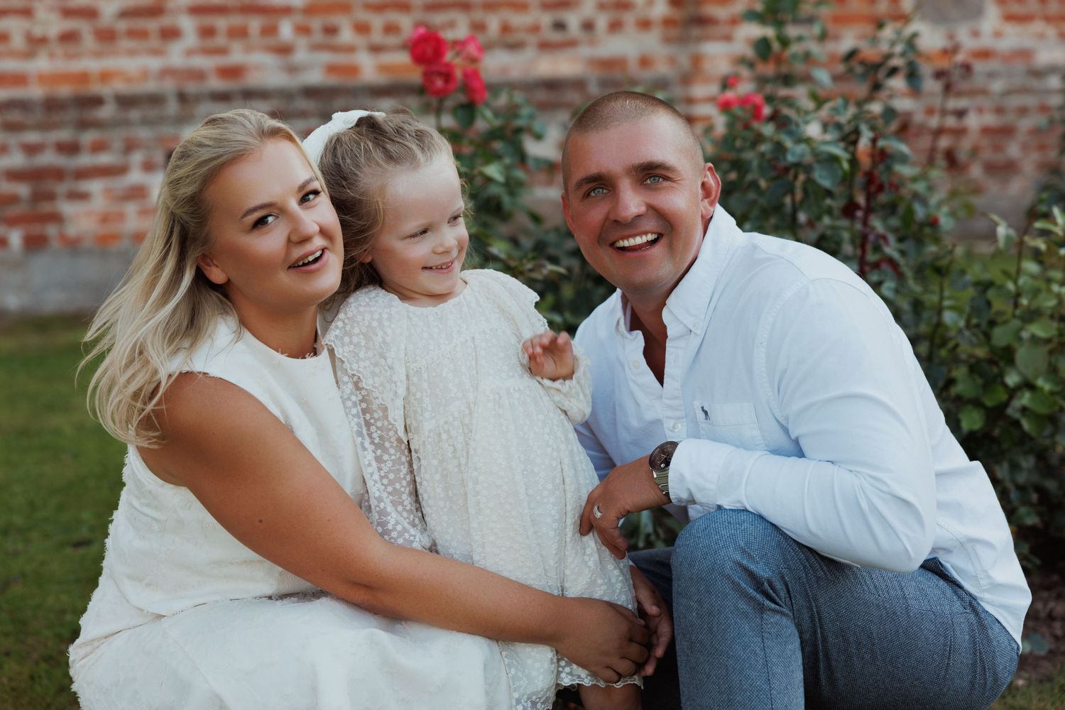 Playful family photoshoot with laughter and embraces by a rose garden.