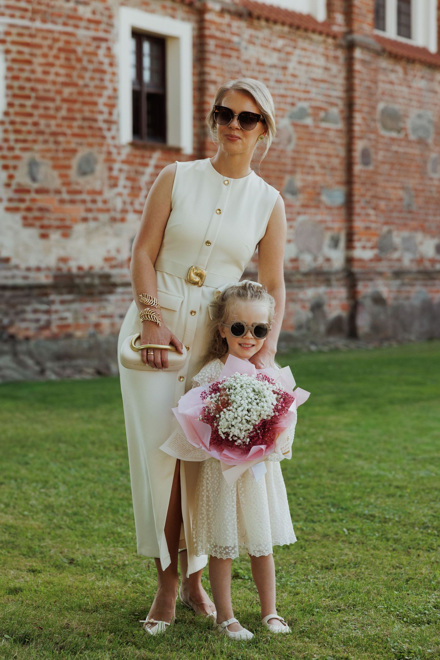 Pink and white floral bouquet held outdoors against brick building background.