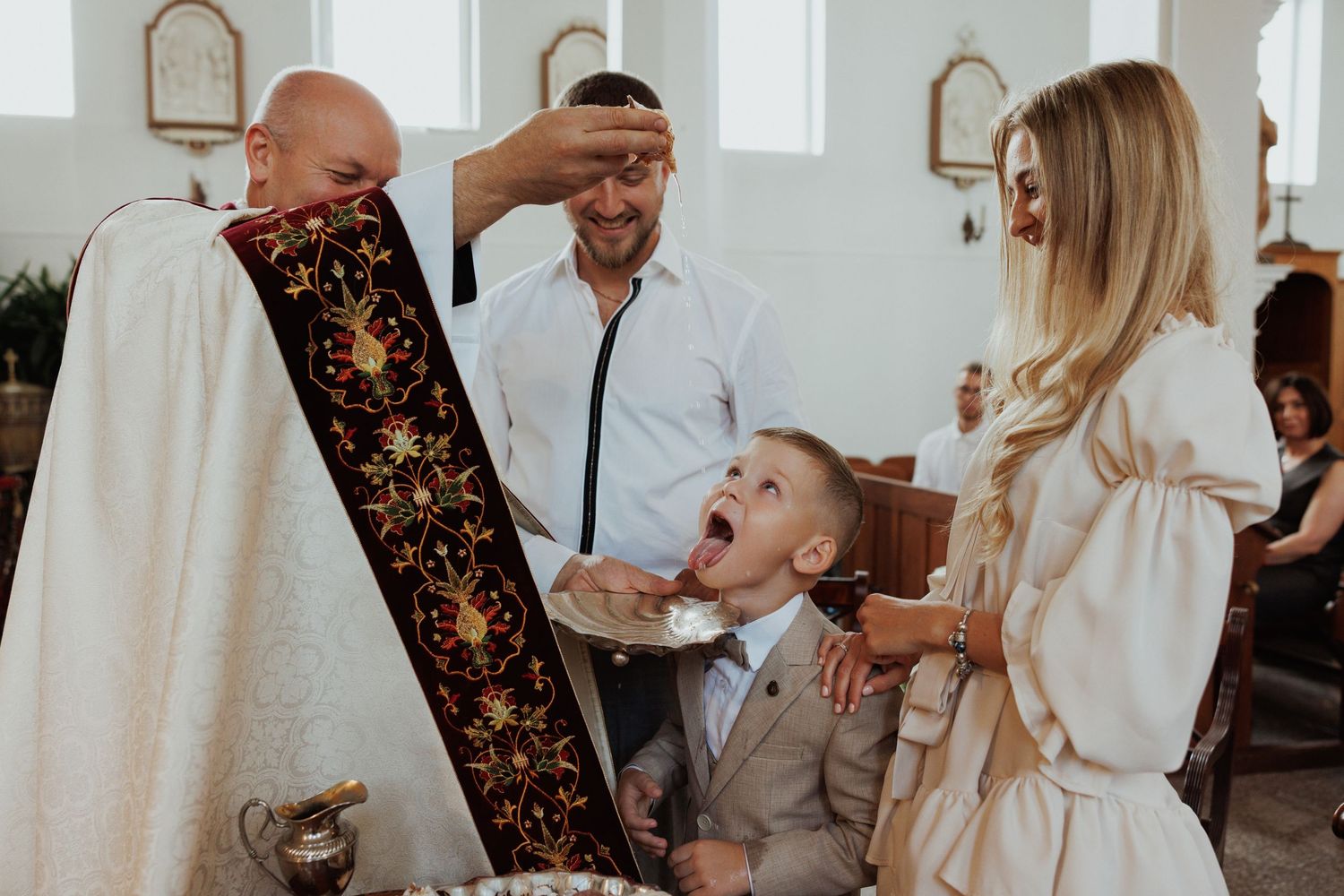 A couple shares an intimate moment during their wedding ceremony in a bright white chapel setting.