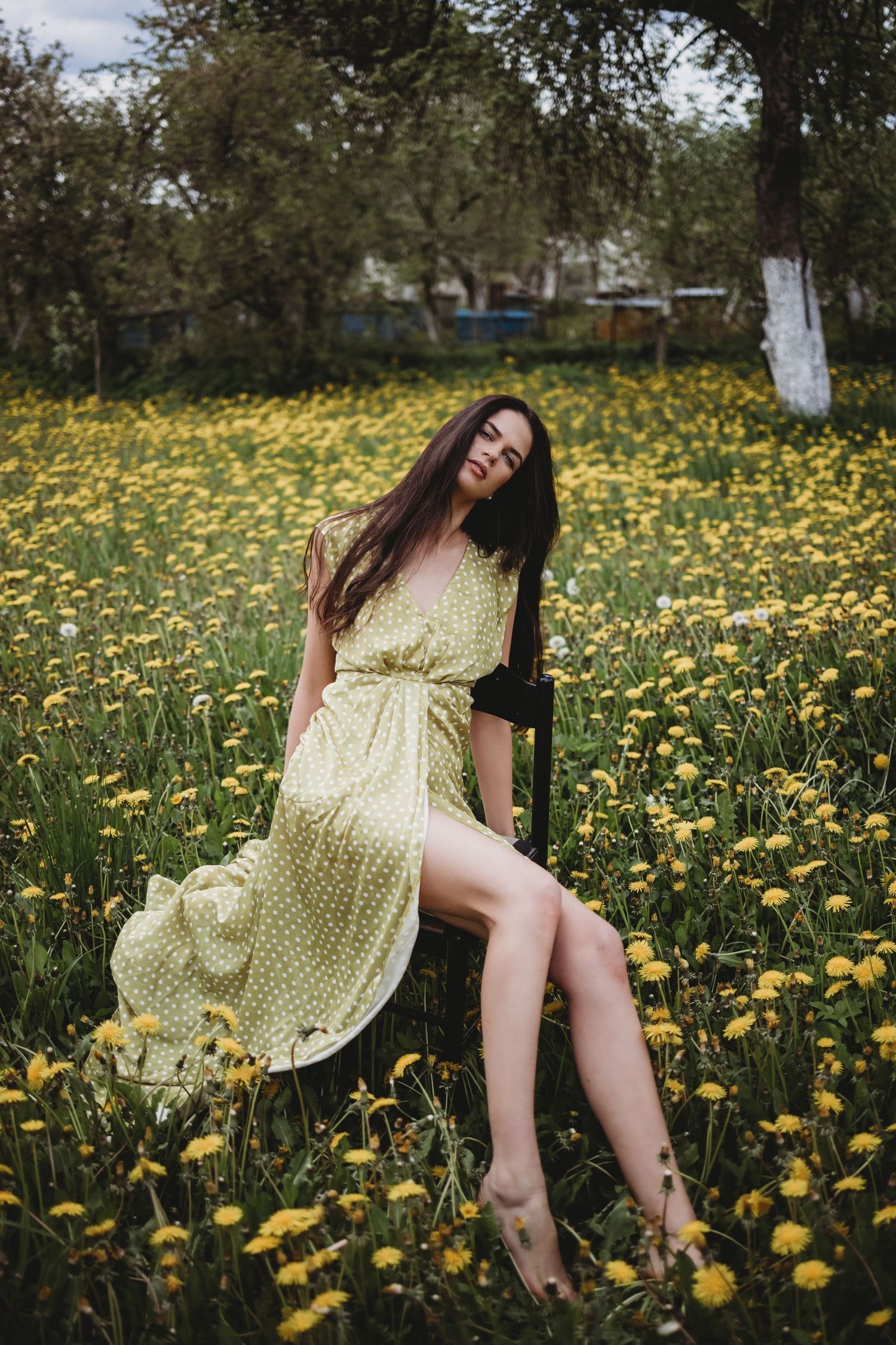 Yellow polka dot dress flows gracefully among blooming dandelions in a spring meadow.