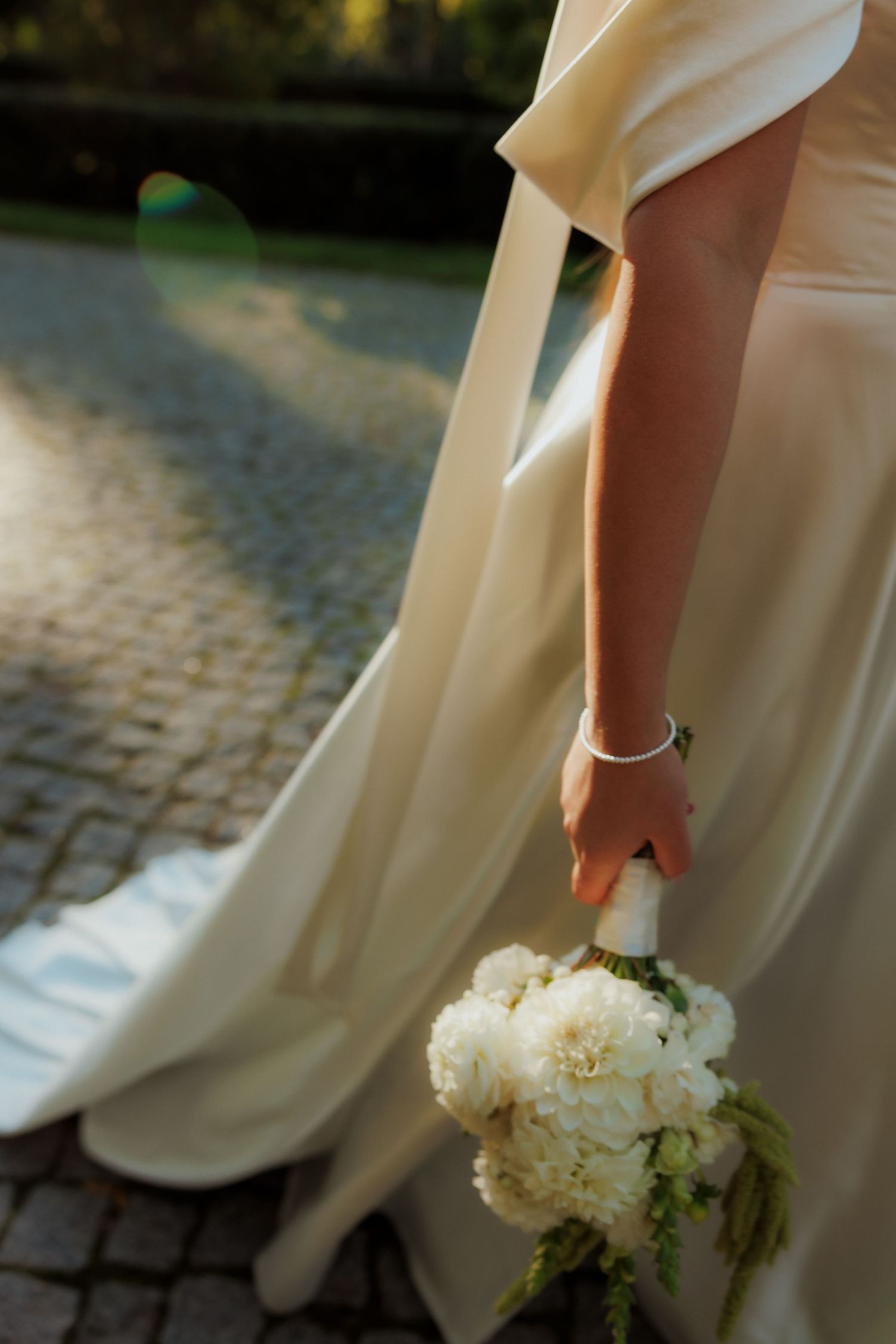 Close-up view of a white wedding bouquet with delicate flowers against a stone pathway.