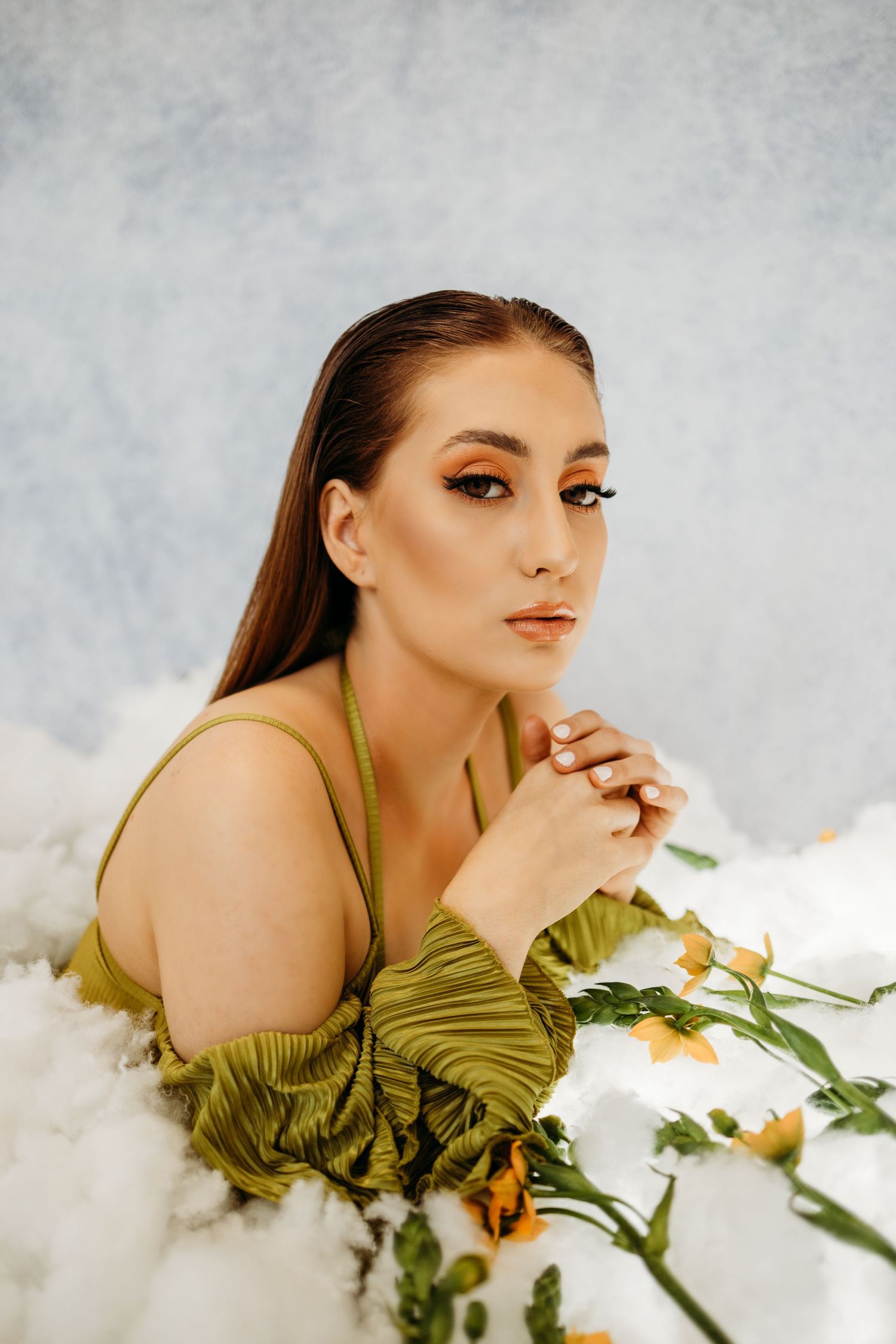 Artistic photo series with flowers and olive green dress on white backdrop.