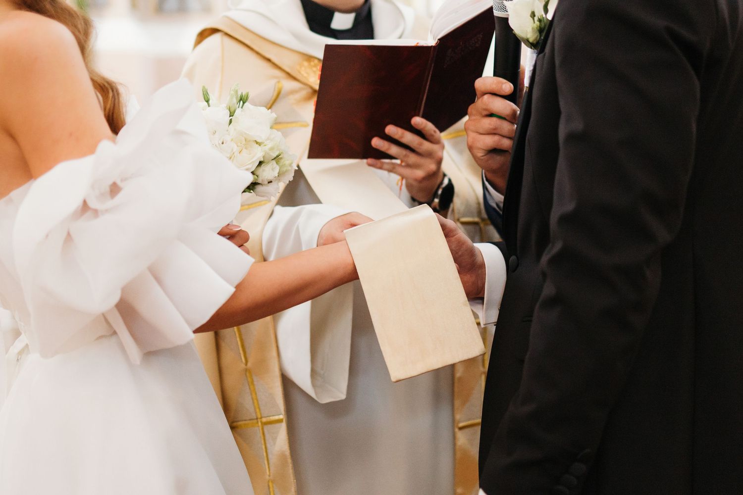 A priest wearing a black clerical collar and white surplice reads from a book during a religious ceremony.