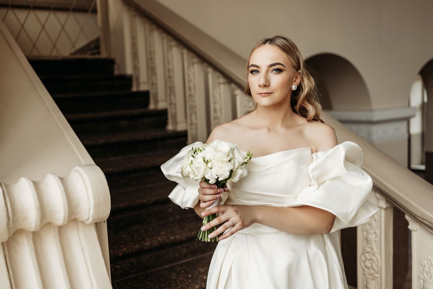 Elegant bridal preparation scene with white wedding dress and plush armchair in natural light.