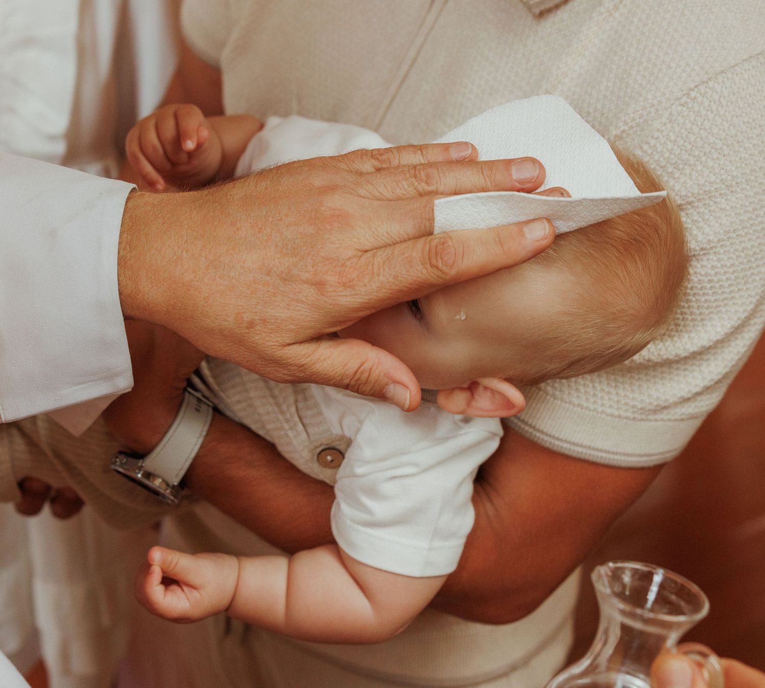 A sequence of hands performing a baby massage technique on an infant's arm in warm, neutral tones.