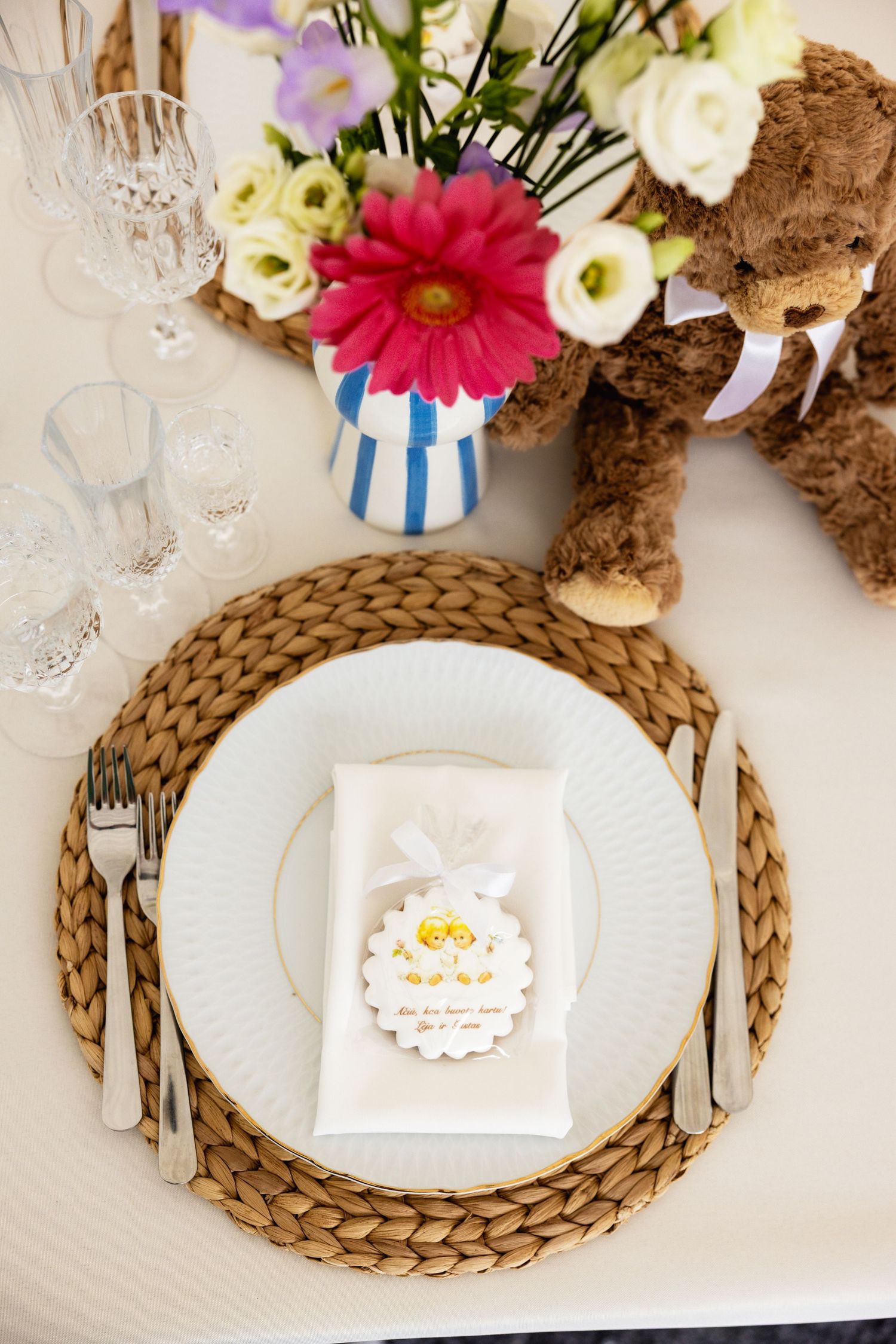Elegant place setting with wicker charger, white plates, and colorful floral arrangements.