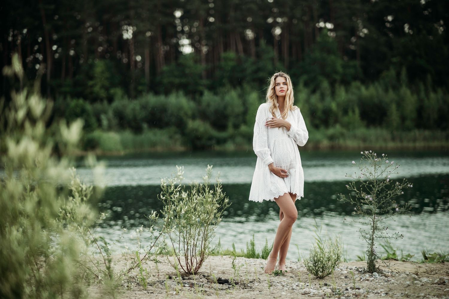 Lakeside maternity photography with white dress and natural scenery.