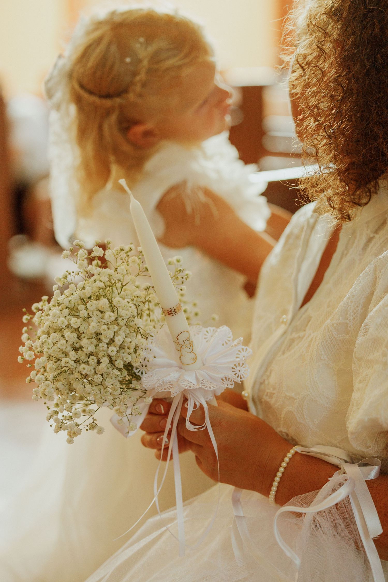 Row of attendants in white dresses holding delicate baby's breath bouquets during a wedding ceremony.