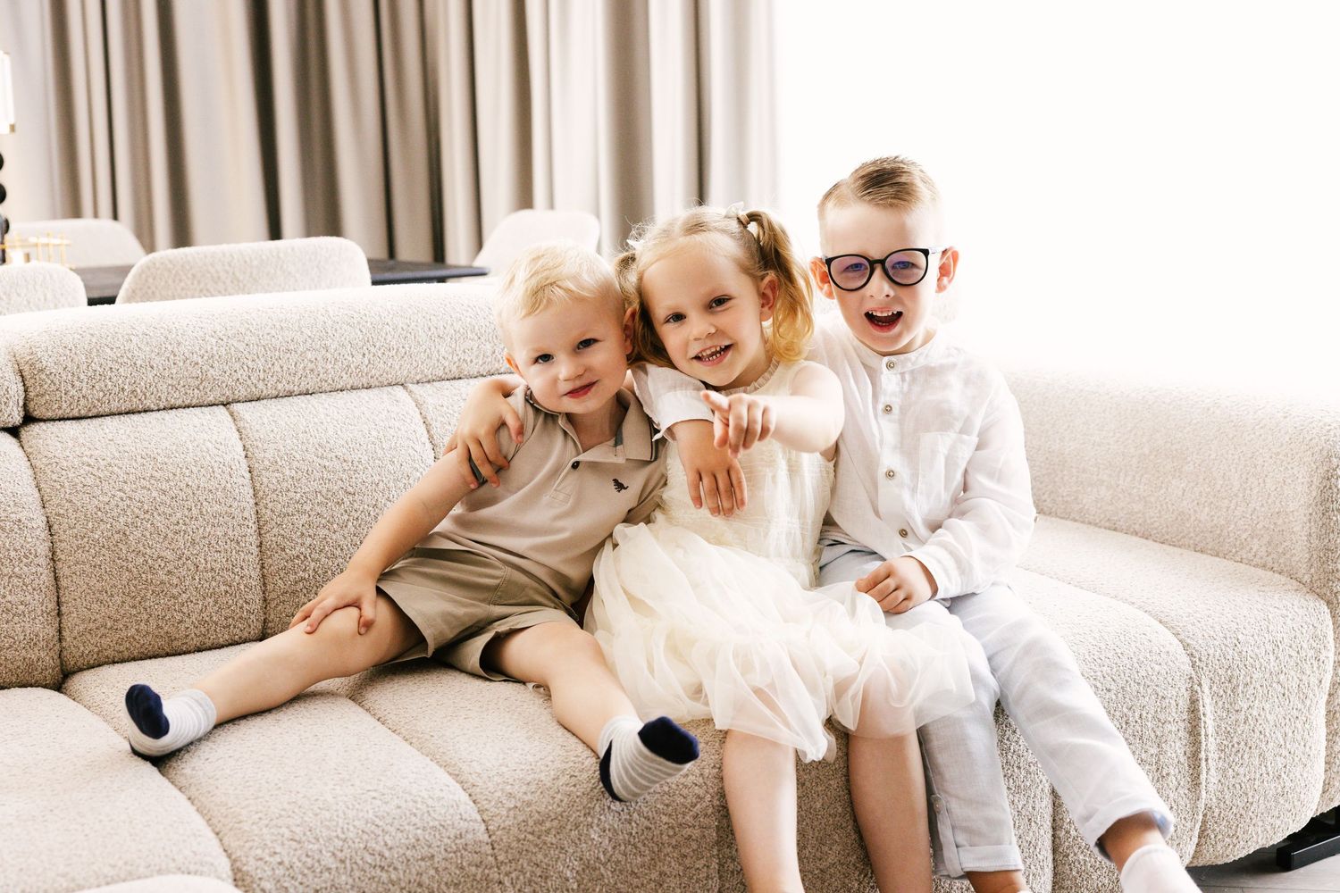 Family relaxing together on a cozy beige couch in a bright living room.